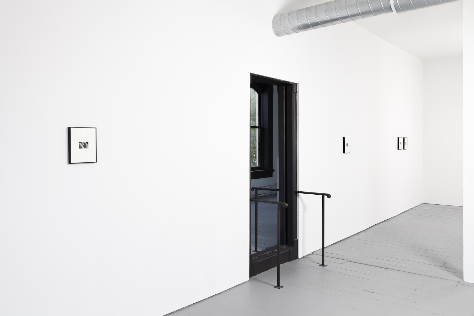 A white room with small images on the wall and a door leading into another room.