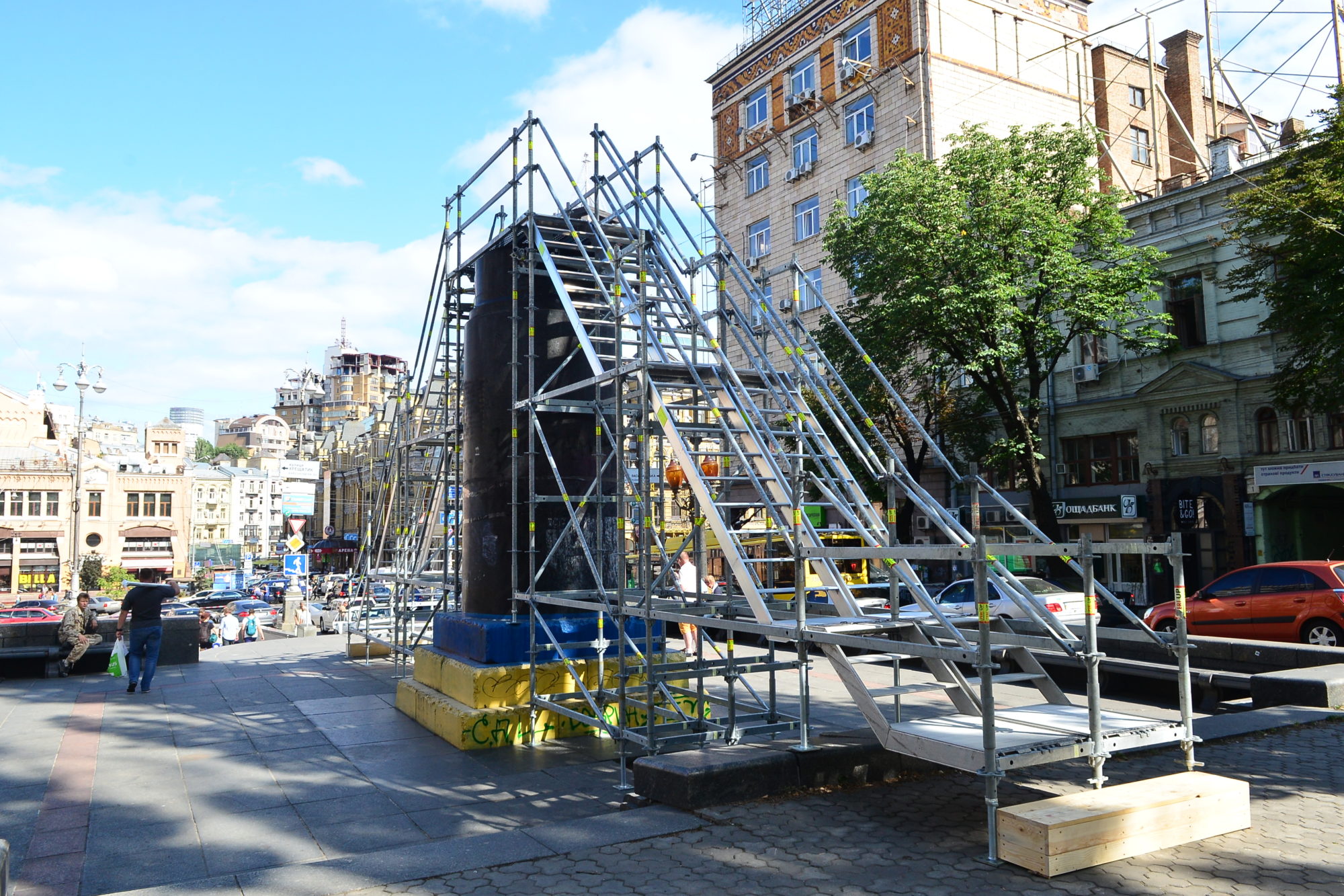 A photograph depicting metal staircases rising to meet over a concrete structure, the staircases are set in an urban setting