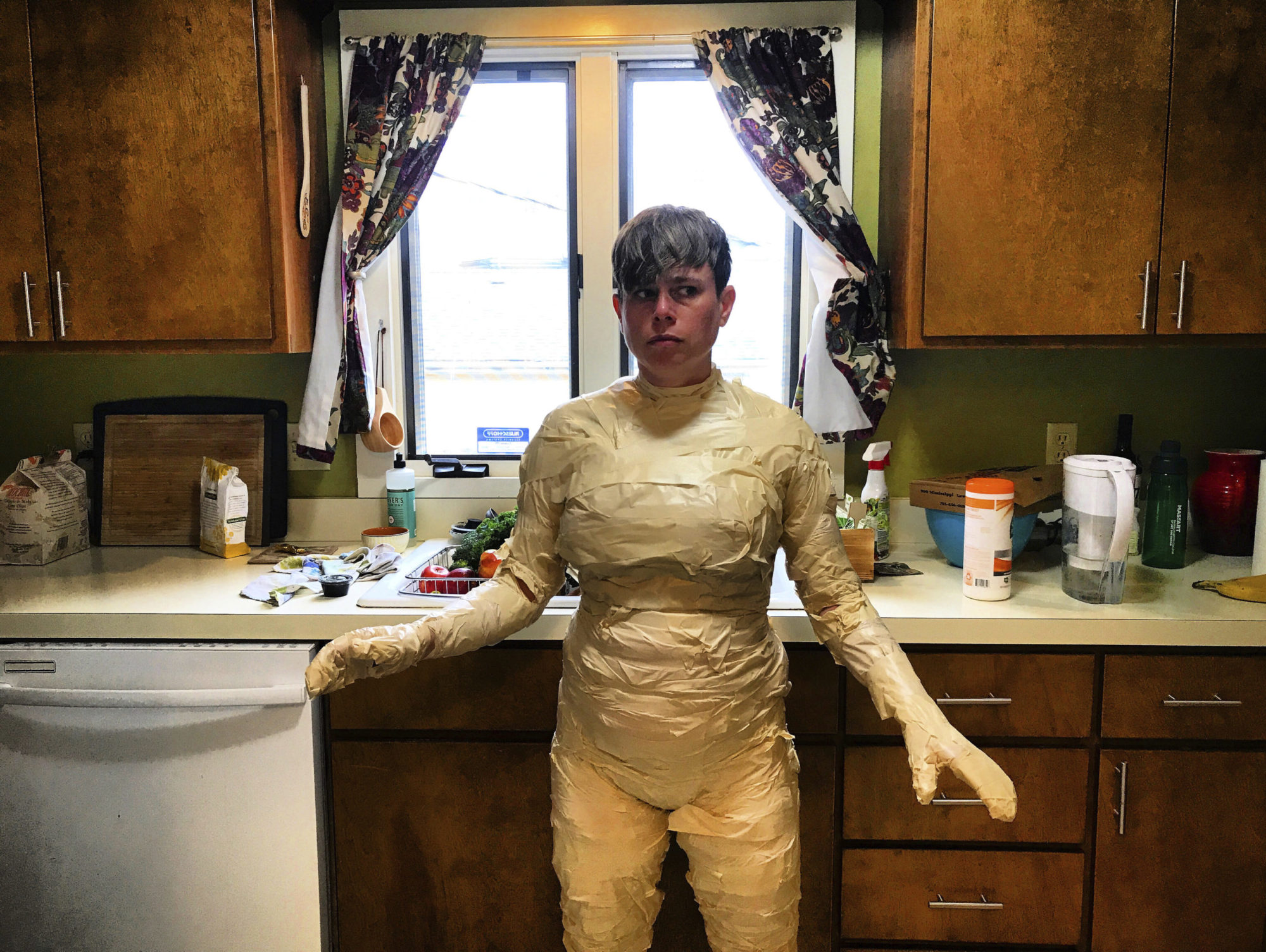 a person standing anxiously in the kitchen, wrapped in tape