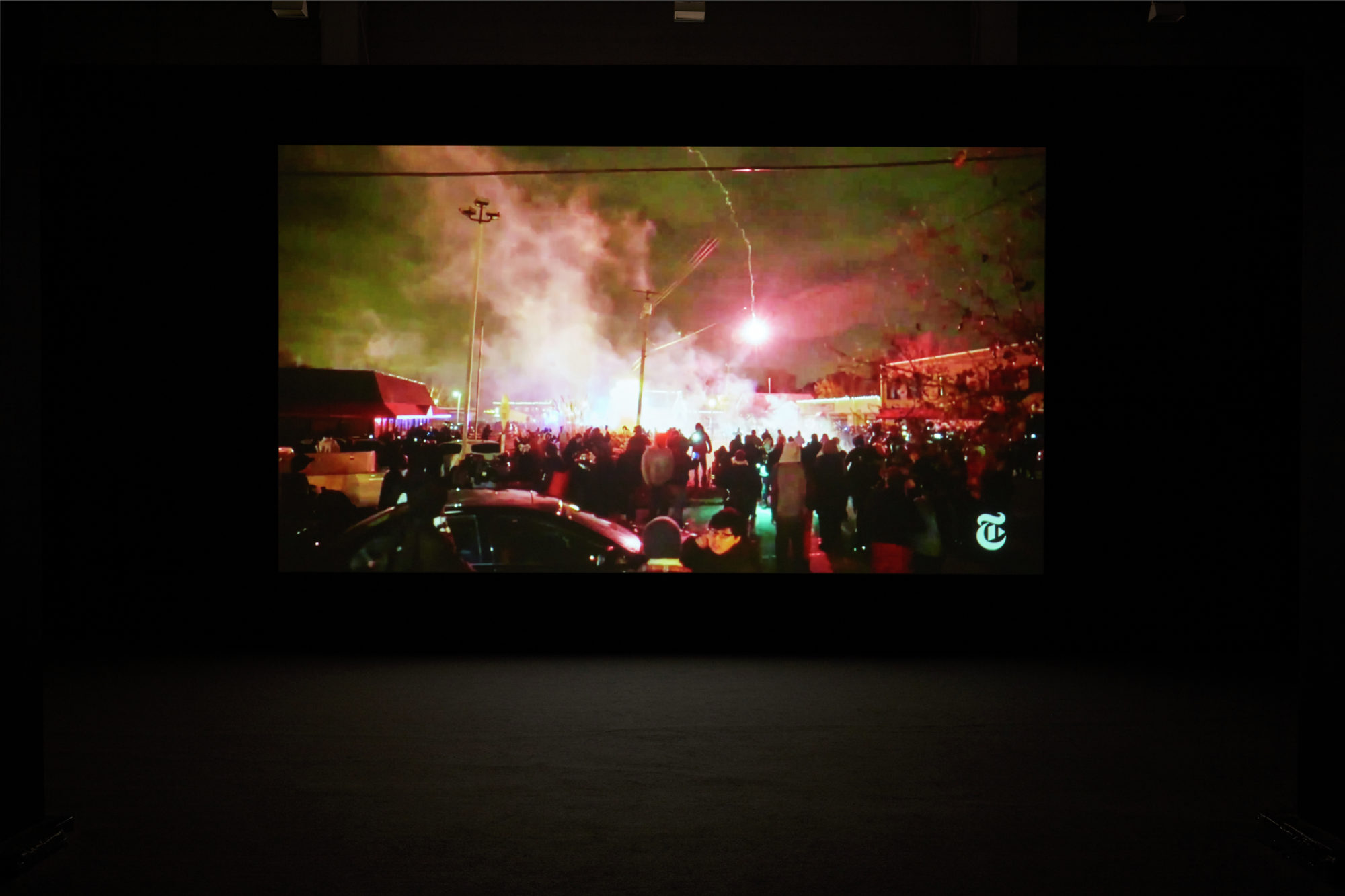 image of a video still depicting a large crowd surrounding a cloud of smoke and fireworks