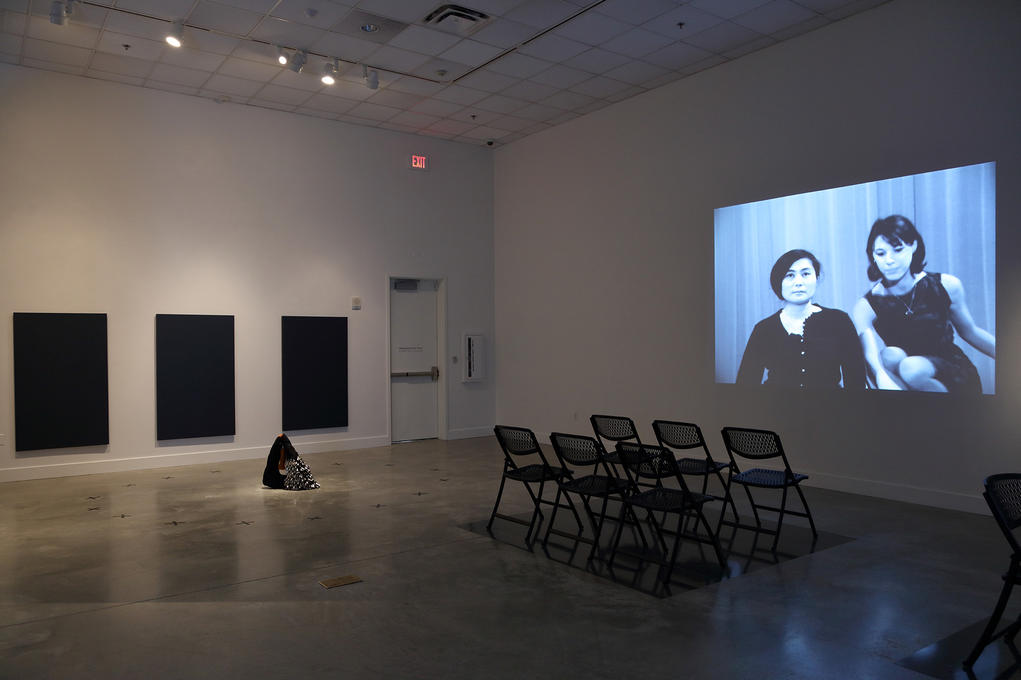 Installation view of a projected video with a group of chairs in front of it