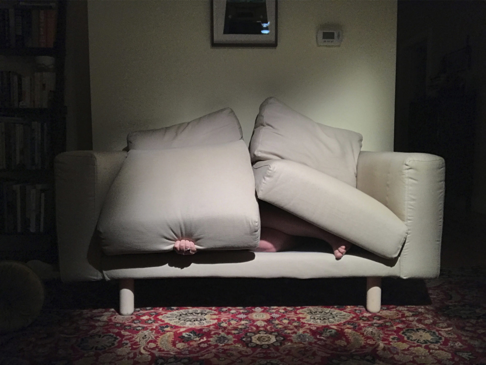 a couch with someone hiding beneath the cushions