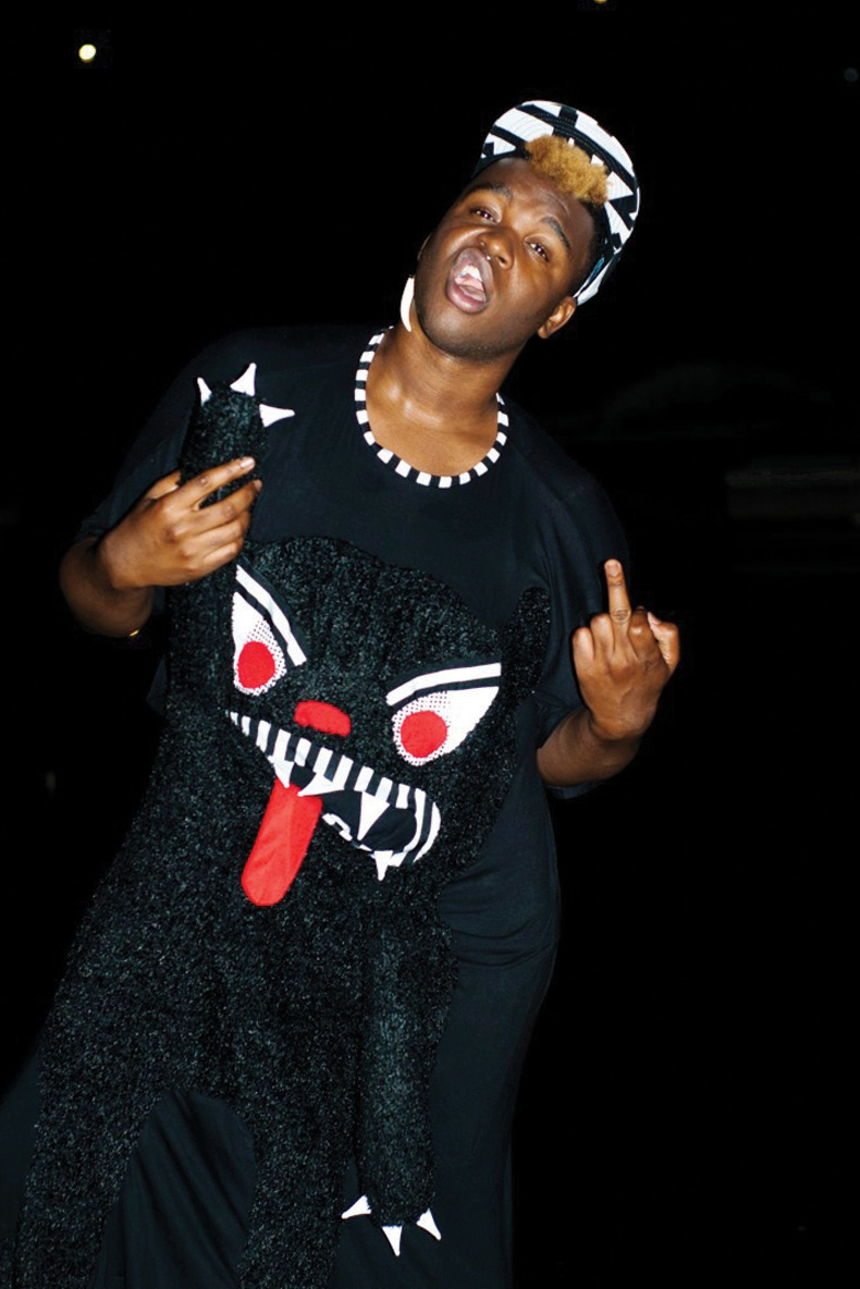 black masc person wearing black clothing with an abstract white and red face on it