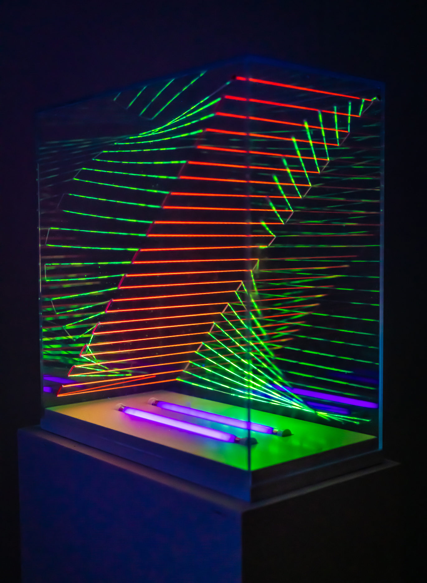 black-lit neon green and orange string enclosed in glass case