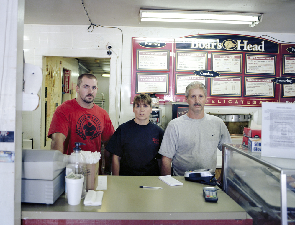 A woman and two men behind the counter at a deli
