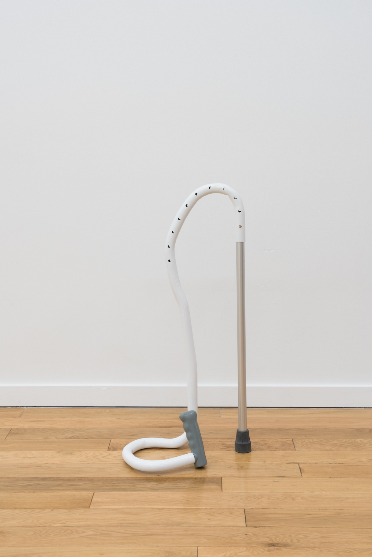 sculpture conveying a metal rod with a black stopper and a white tube coming out the top