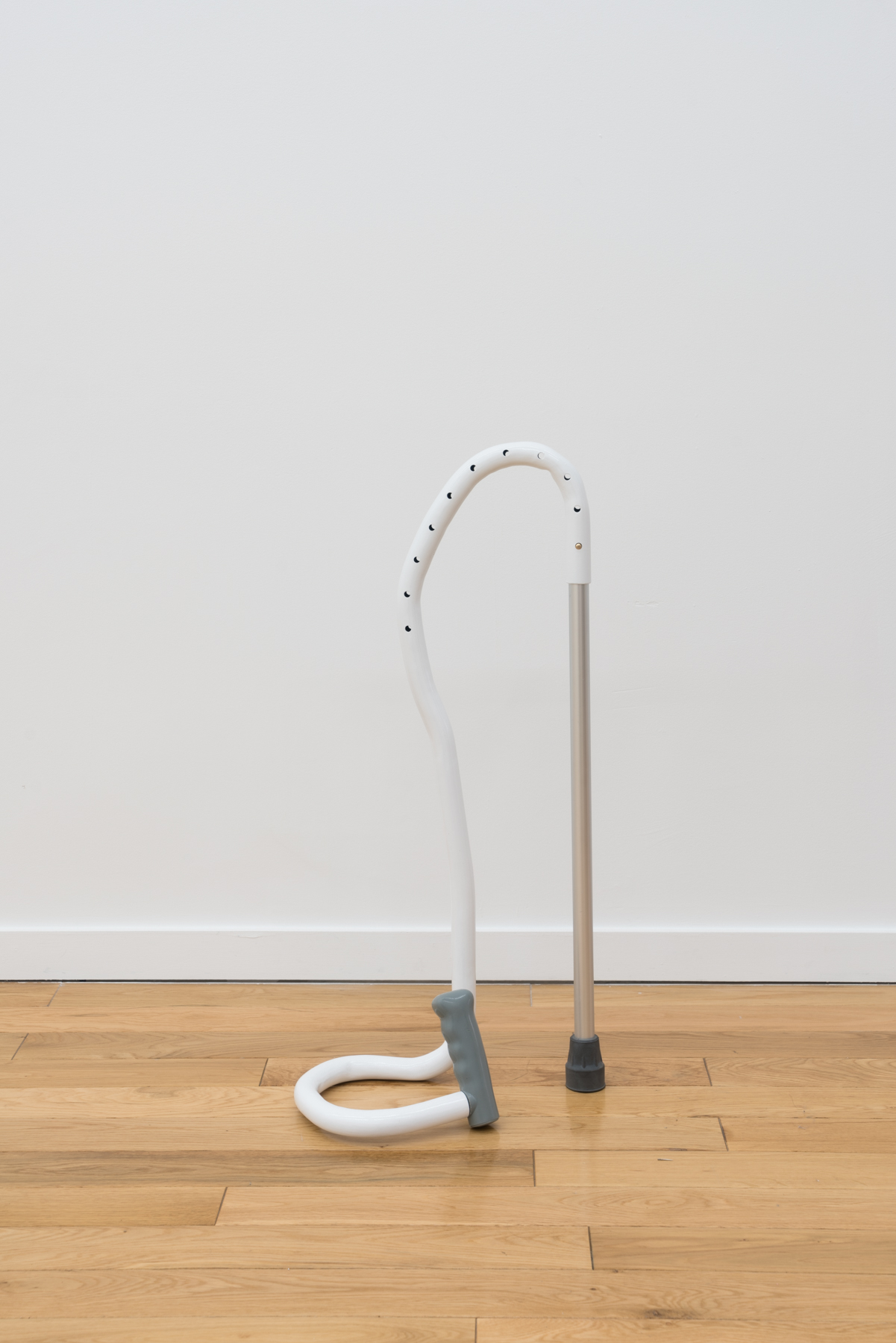 sculpture conveying a metal rod with a black stopper and a white tube coming out the top