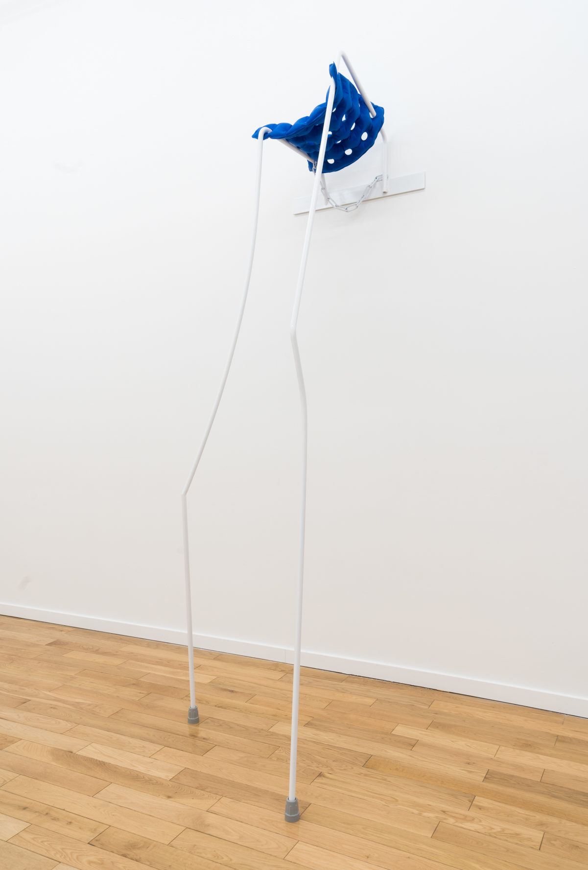 blue sculpture coming off wall attached to white rods that flow down in a funny structure and have gray stoppers