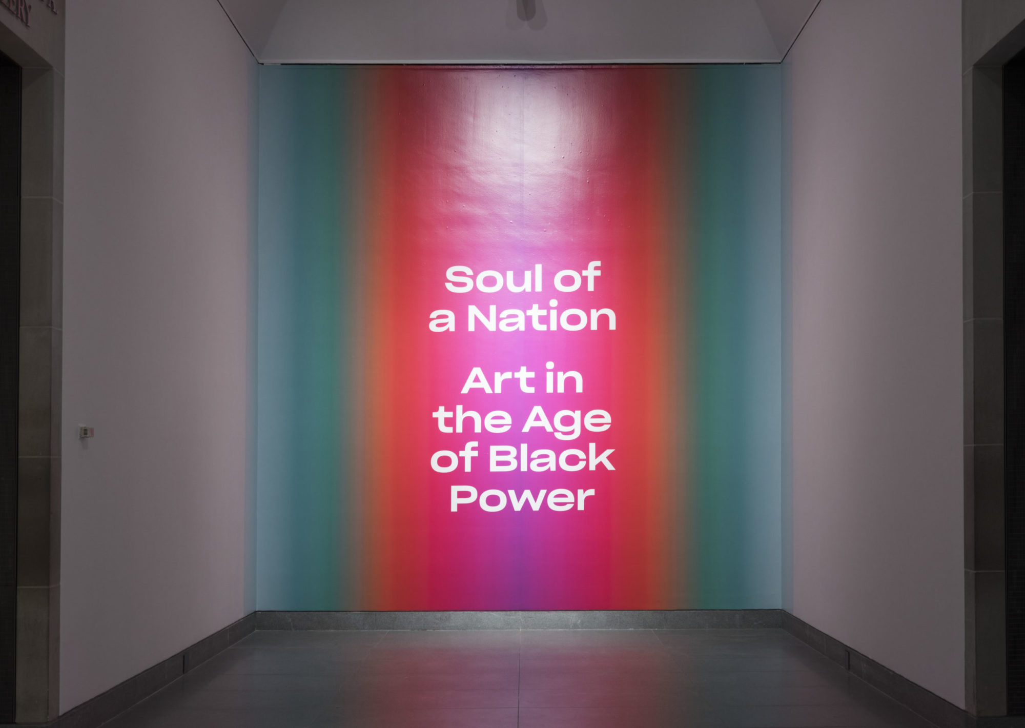A wall spotlit reads 'Soul of a Nation: Art in the Age of Black Power' in white text on a teal, blue, orange and pink background