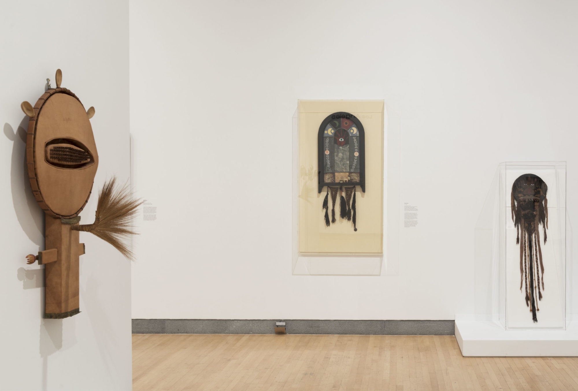 Installation view of 'Soul of a Nation;' three works featuring natural objects such as cloth, feather and beads are in the foreground and background of the image