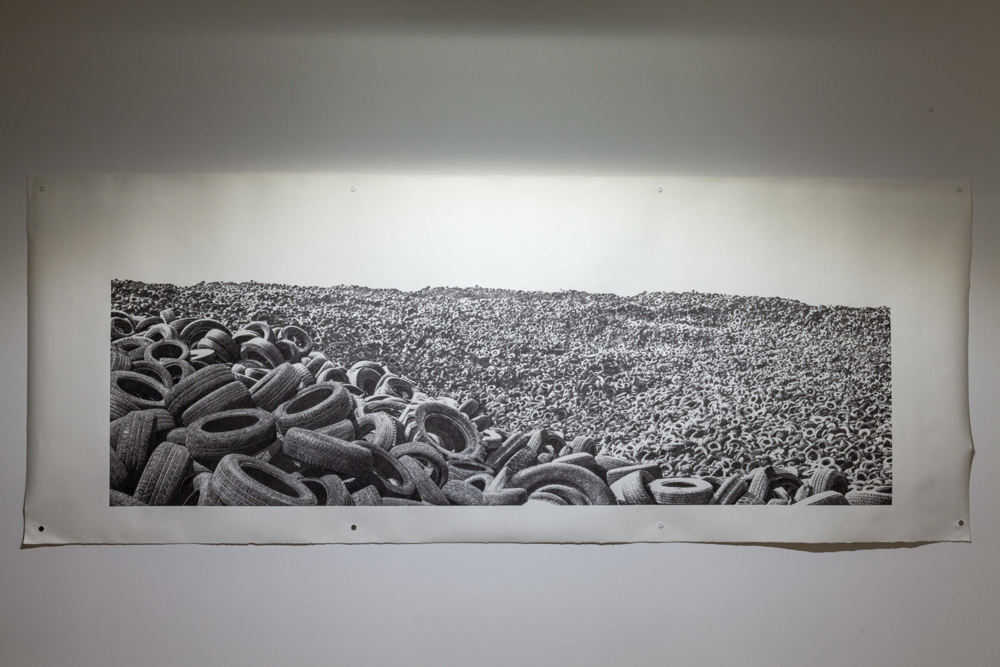 Installation view of a black and white photograph of used tires.