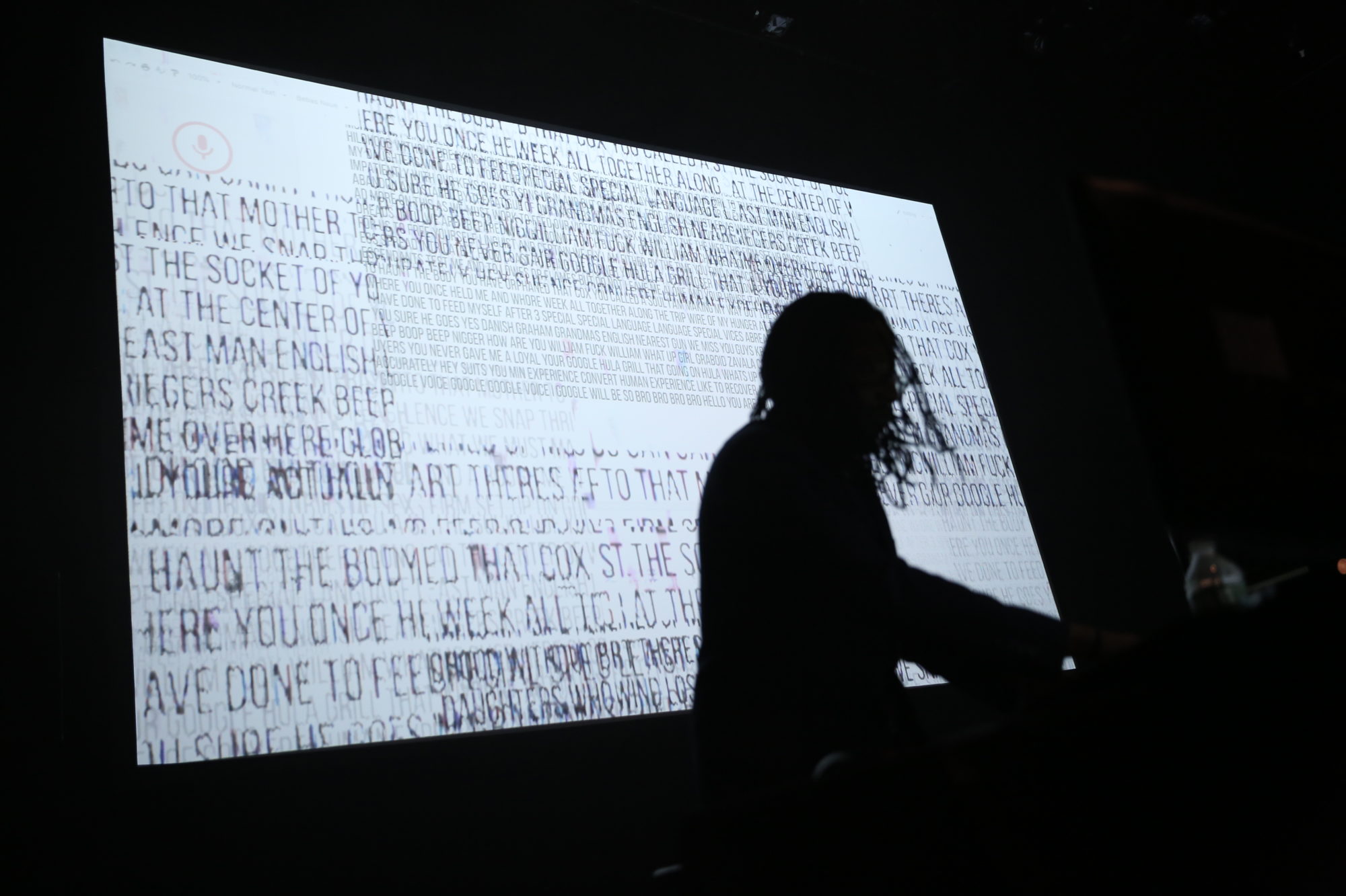 Silhouette of person in front of projection of text.