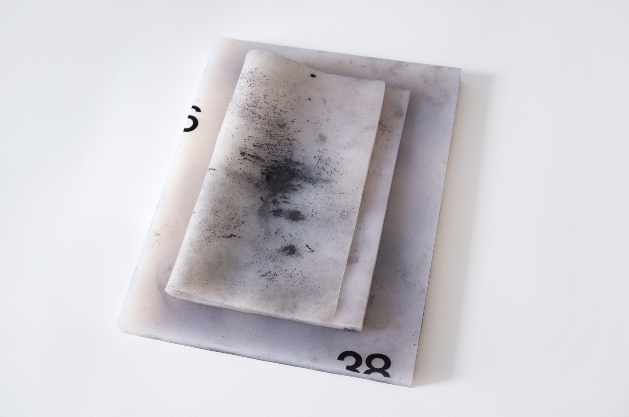 Two flesh toned silicone rectangles sit on top of one another covered in crushed graphite smudges. The number 38, cut off by the edge, sits in the bottom right corner.