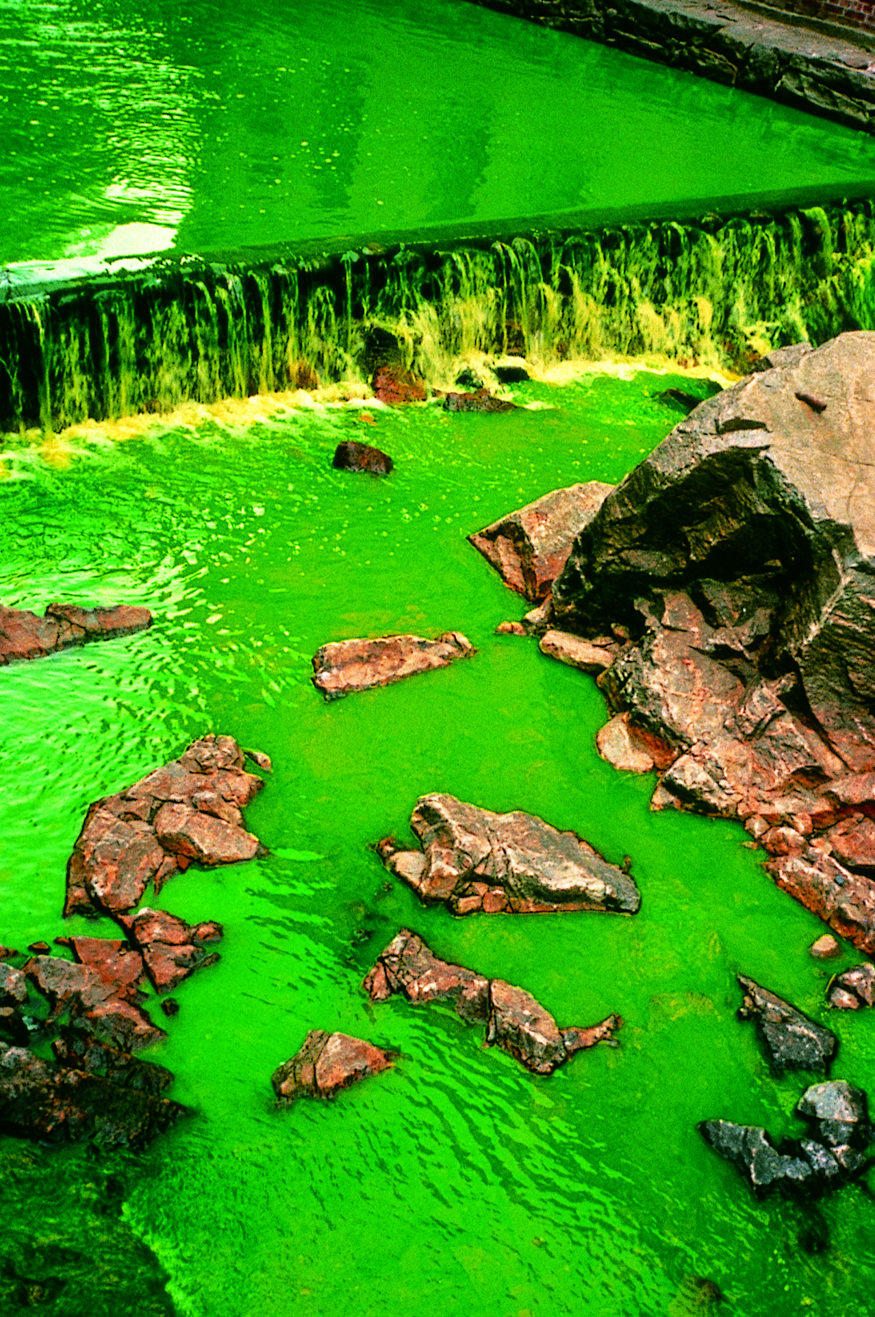 A green tinted waterfall with rocks.