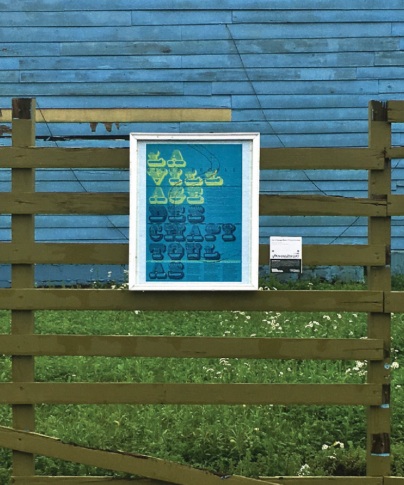 A photo of a framed blue poster hanging on a wooden fence.