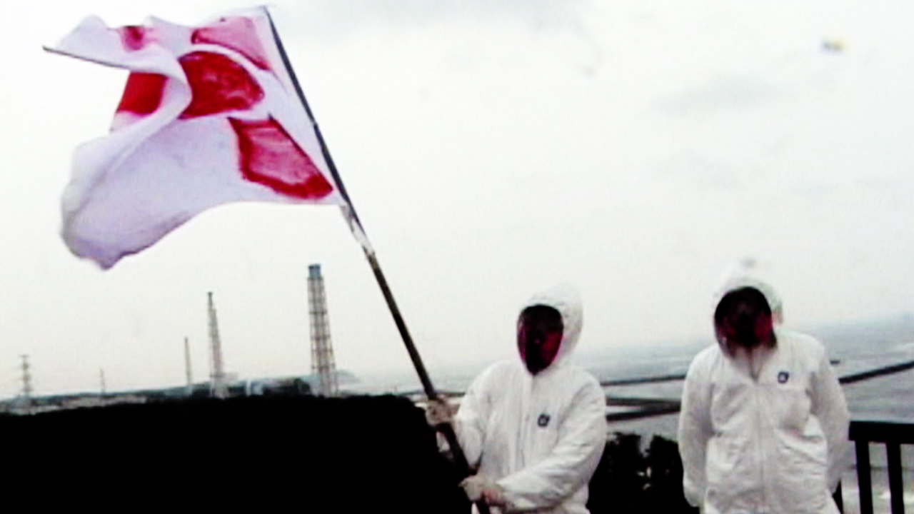 Two figures in white suits, one is holding a flag