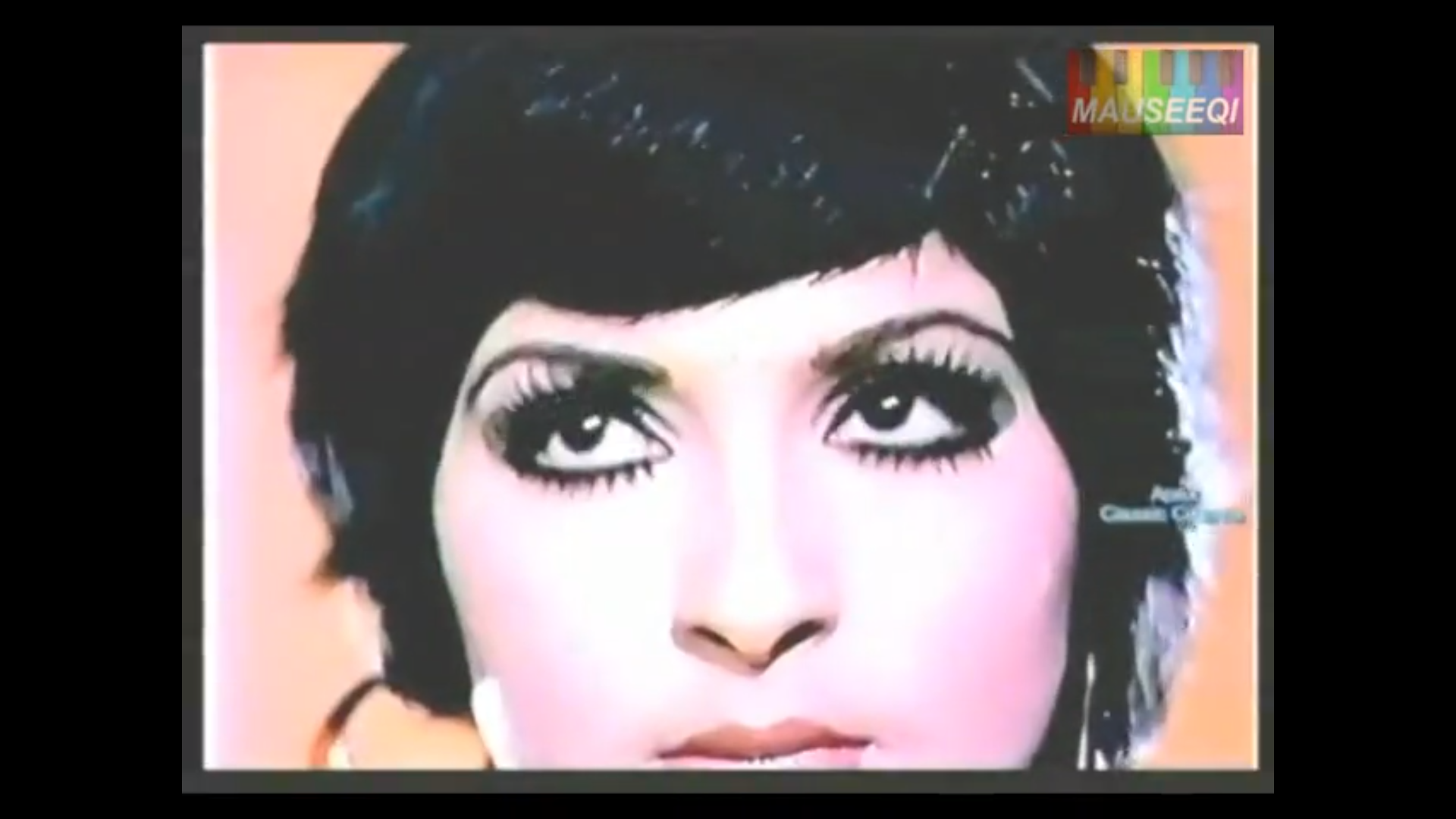 A screenshot of a closeup of a Pakistani actress with glamorous eyelashes gazing upwards; the watermark in the upper right corner reads 'mauseeqi' and another watermark on the right side reads 'Apex Classic Cinema'