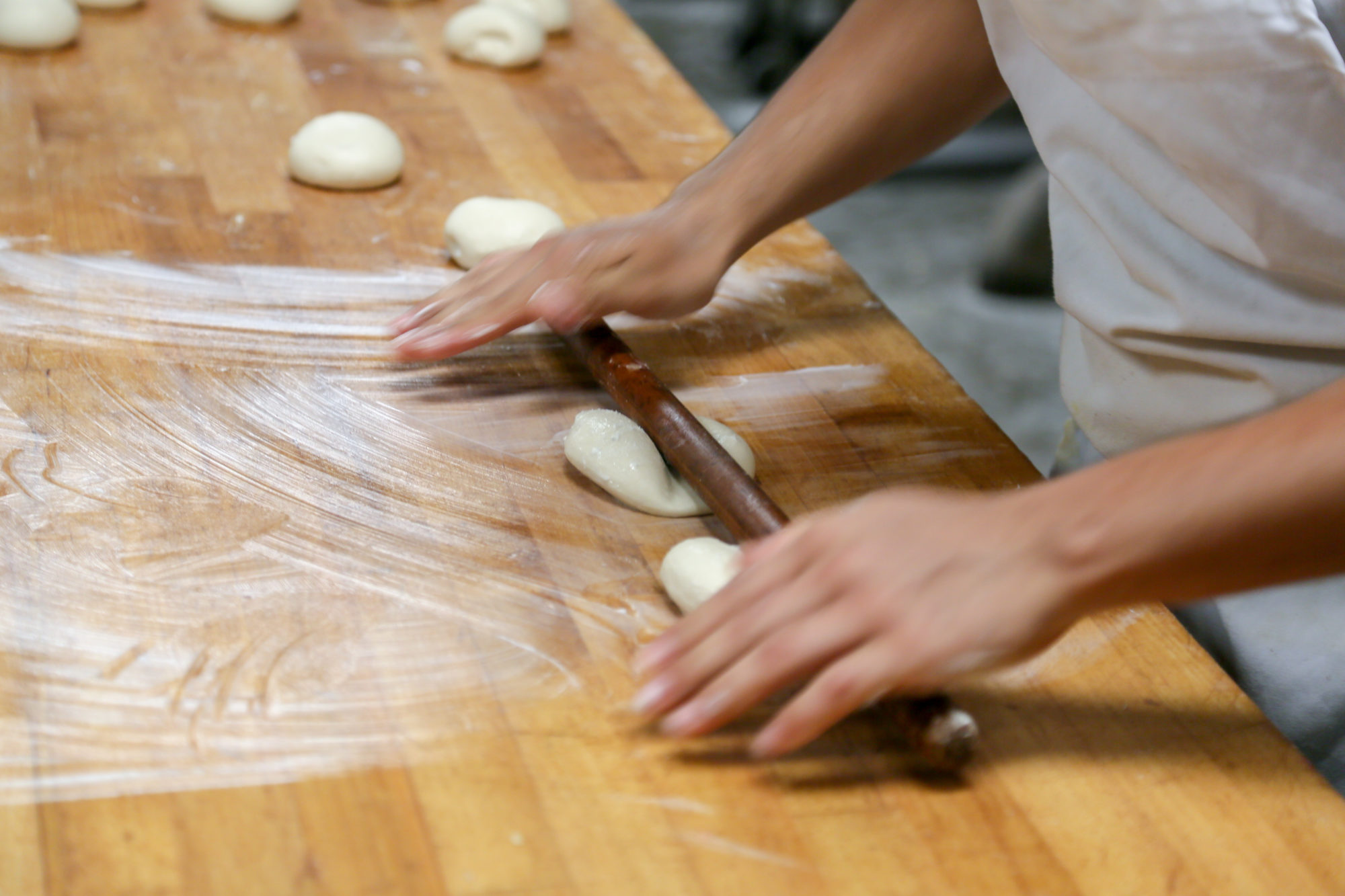 Hands using a rolling pin to flatten dough