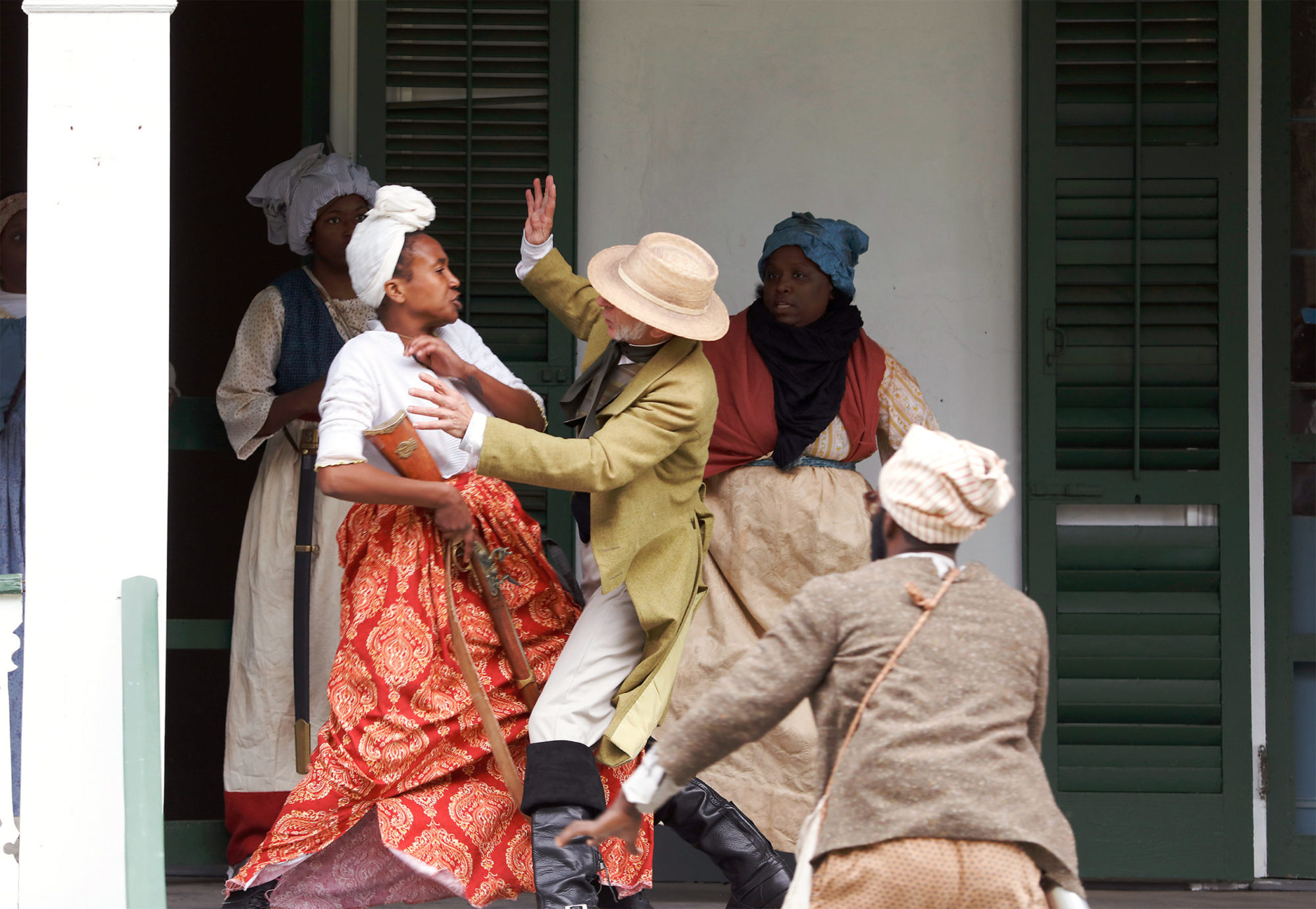 Documentation of the Slave Rebellion Reenactment, a White man in historical dress confronts a gun-wielding Black woman in historical dress