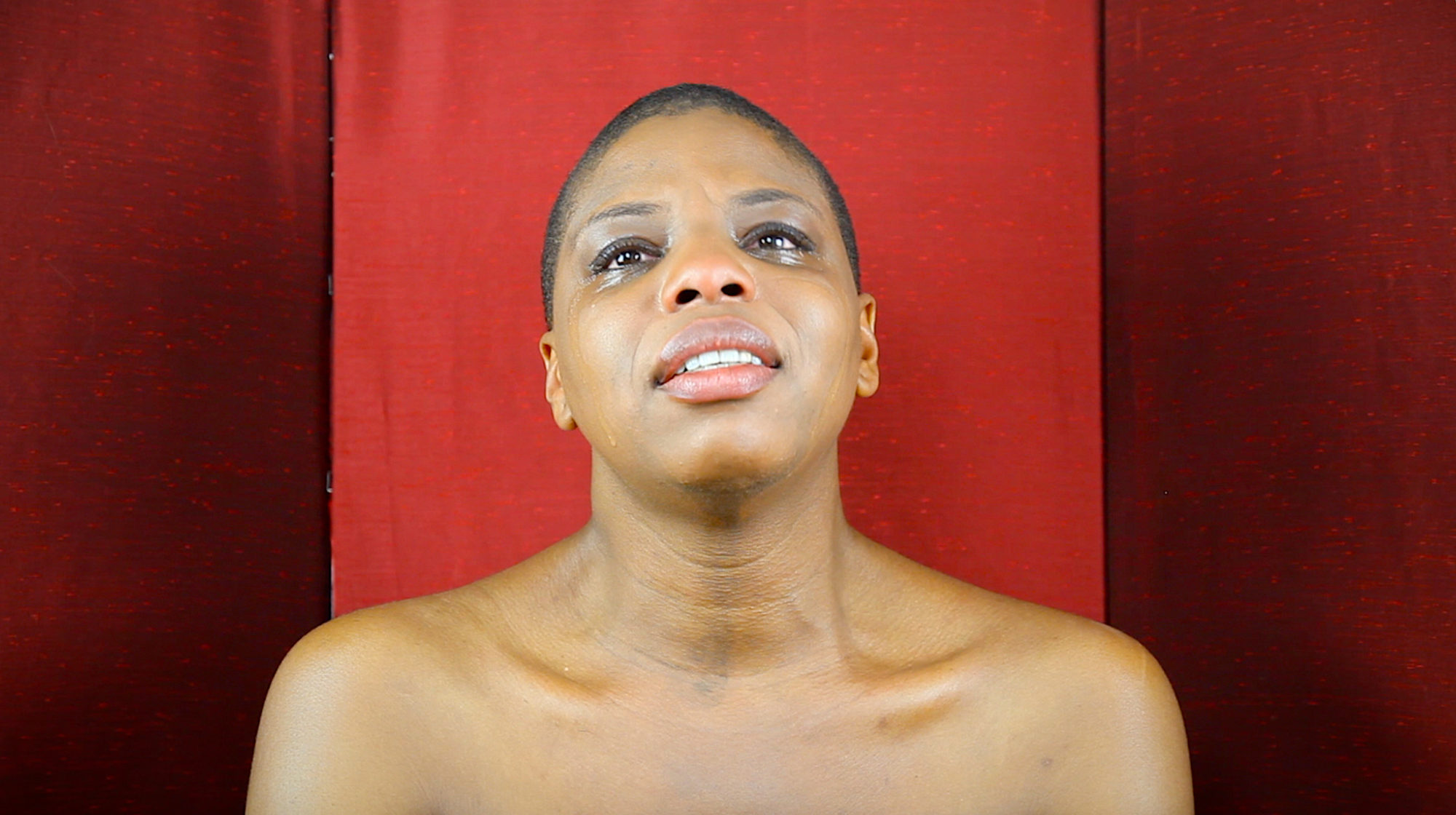 headshot of person crying in front of red backdrop