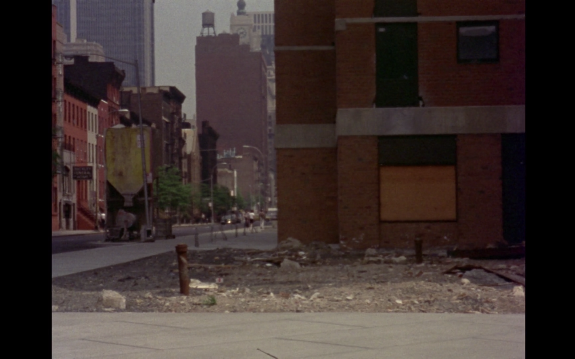 Screenshot from film News From Home of an empty lot in an urban area
