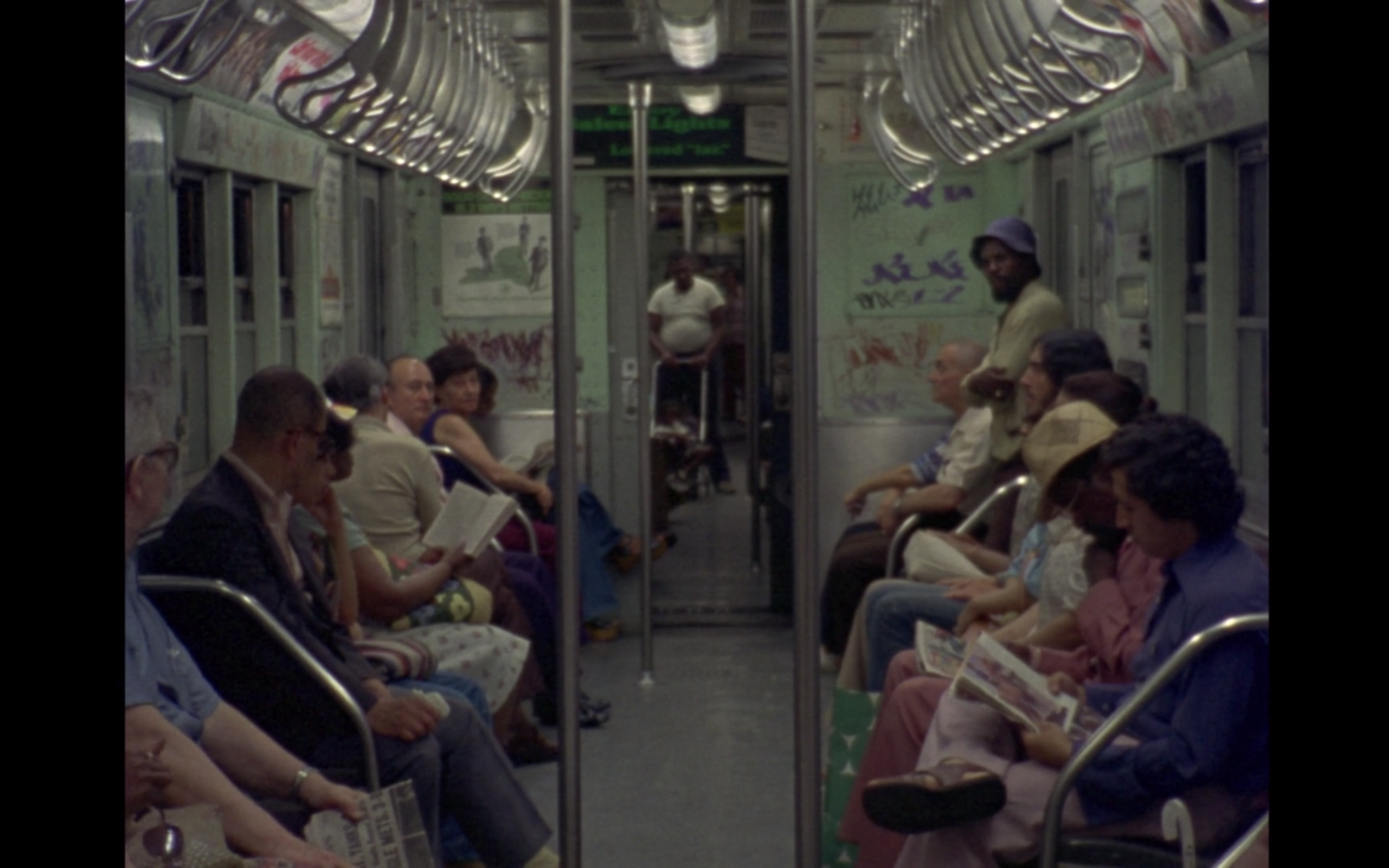 Screenshot from film News From Home displaying a group of individuals sitting on the city train