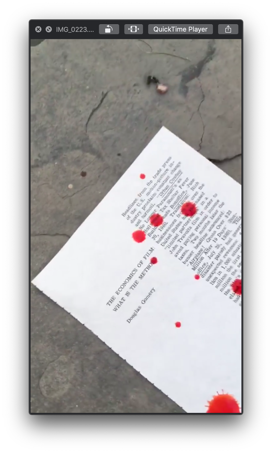 A screenshot of a QuickTime video that depicts a piece of paper on a concrete floor. The paper, seemingly titled 