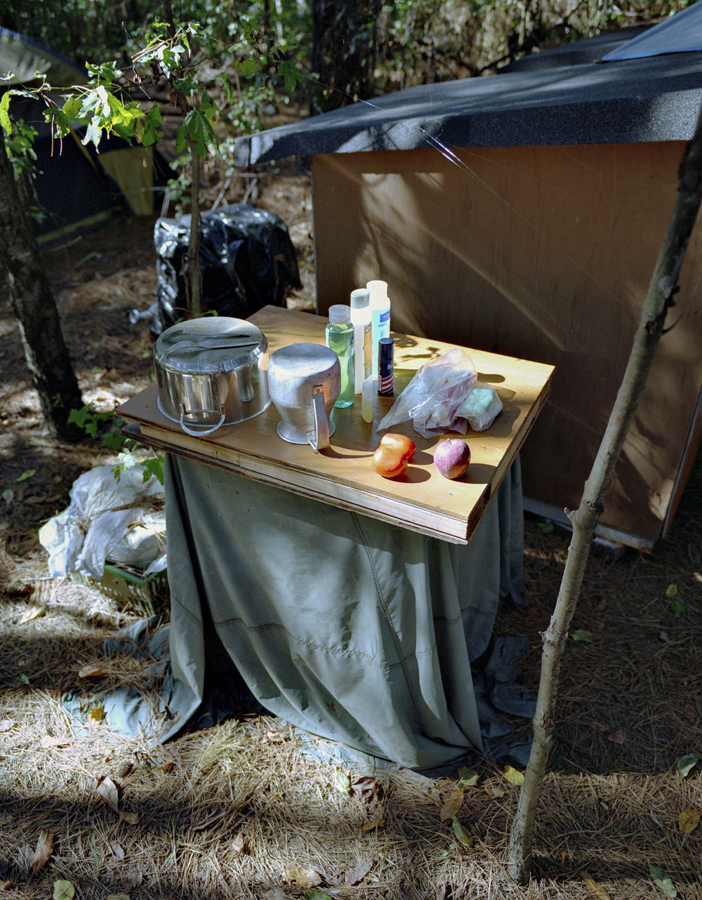 A makeshift table holds supplies and food, next to tents