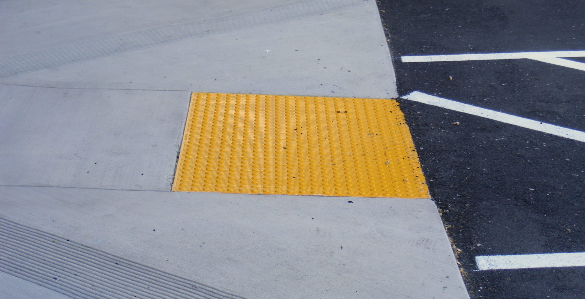 Yellow truncated domes on a sidewalk before a crosswalk