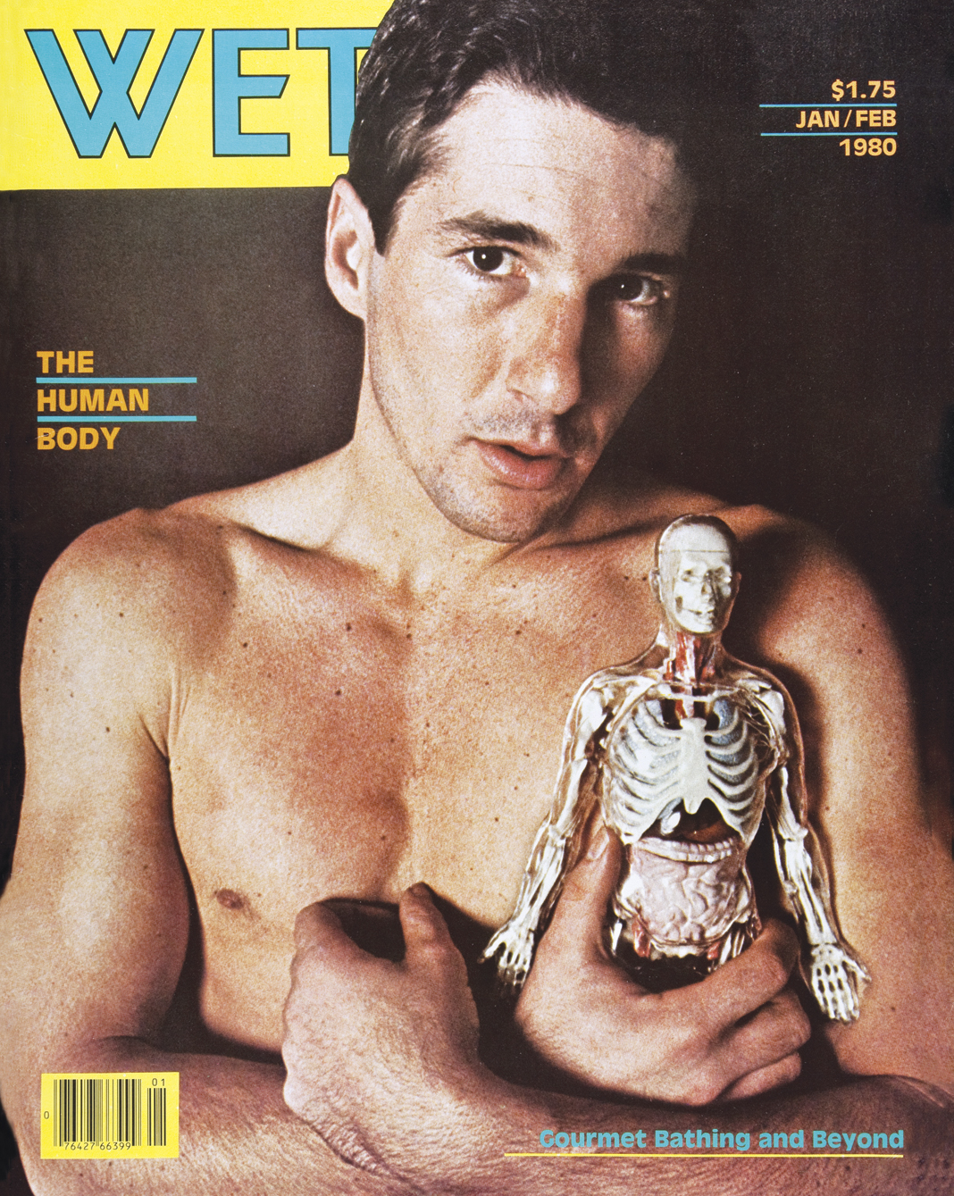 The Human Body cover of WET magazine, featuring a topless male holding a small sized human skeleton replica.