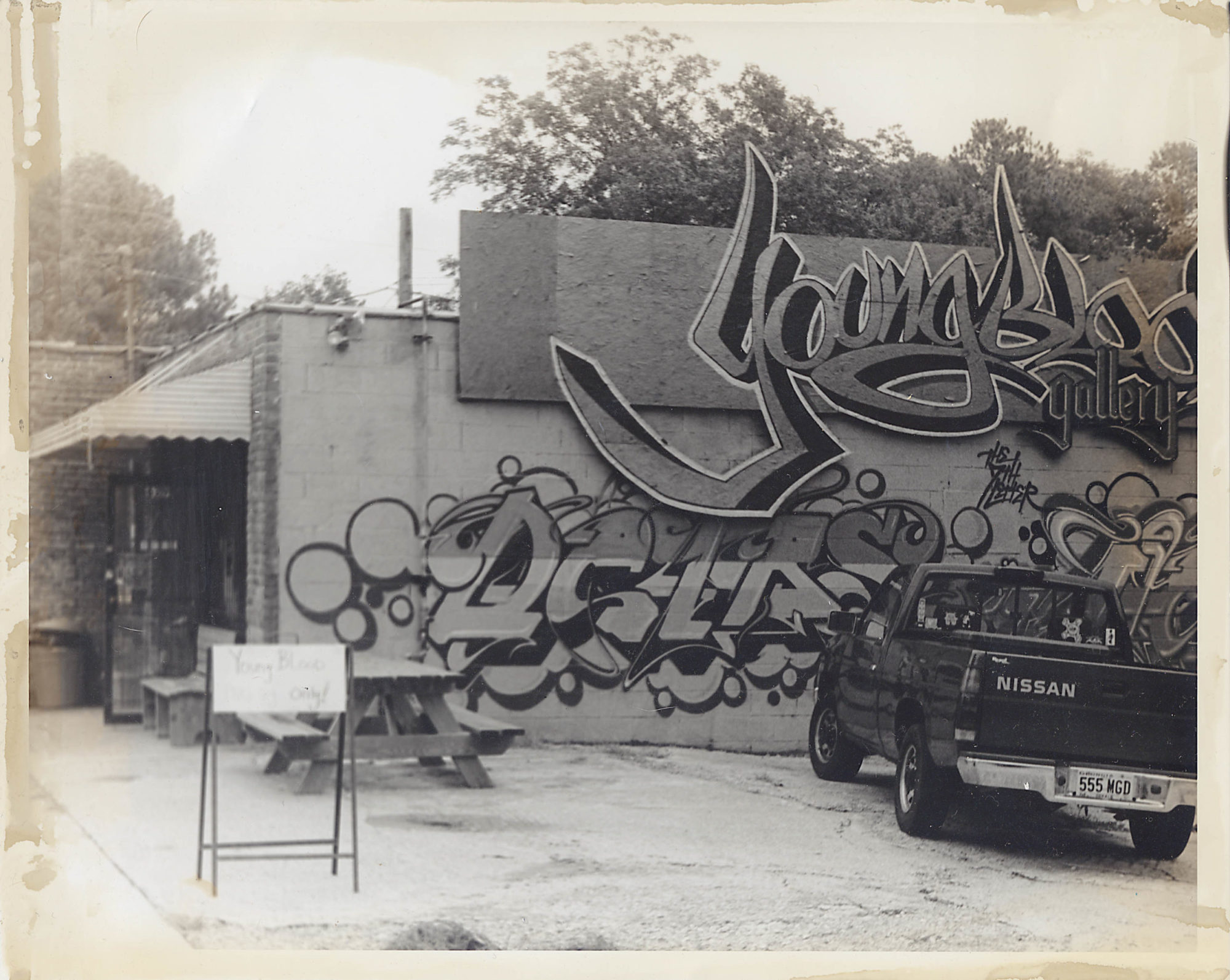 A black and white photograph of the exterior of Young Blood Gallery, where the words 