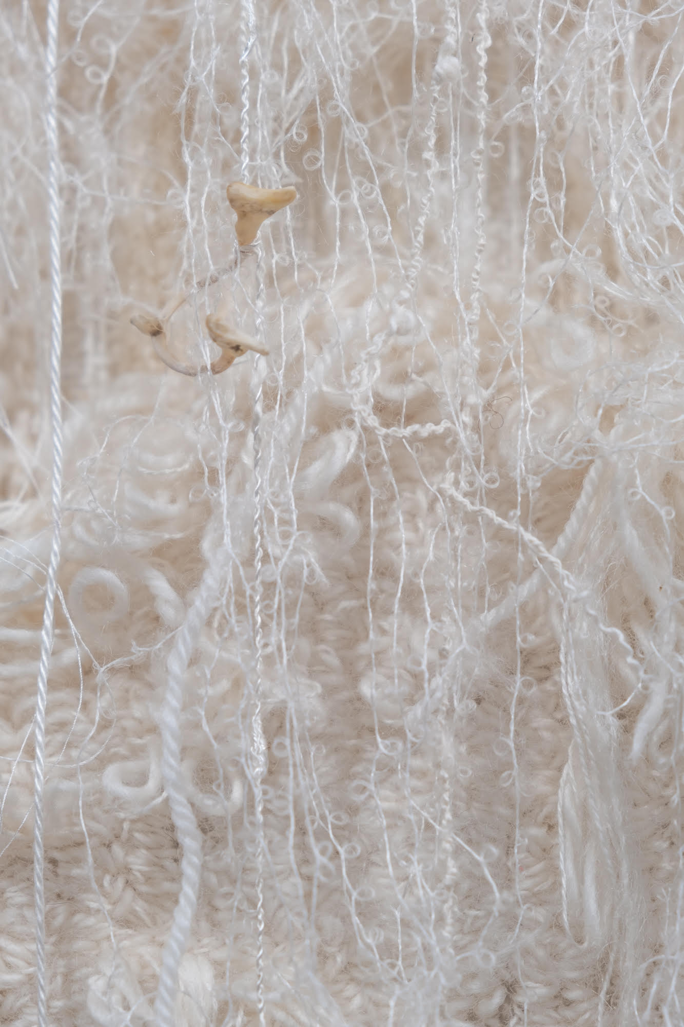 Close-up of work made of yarn and bones.