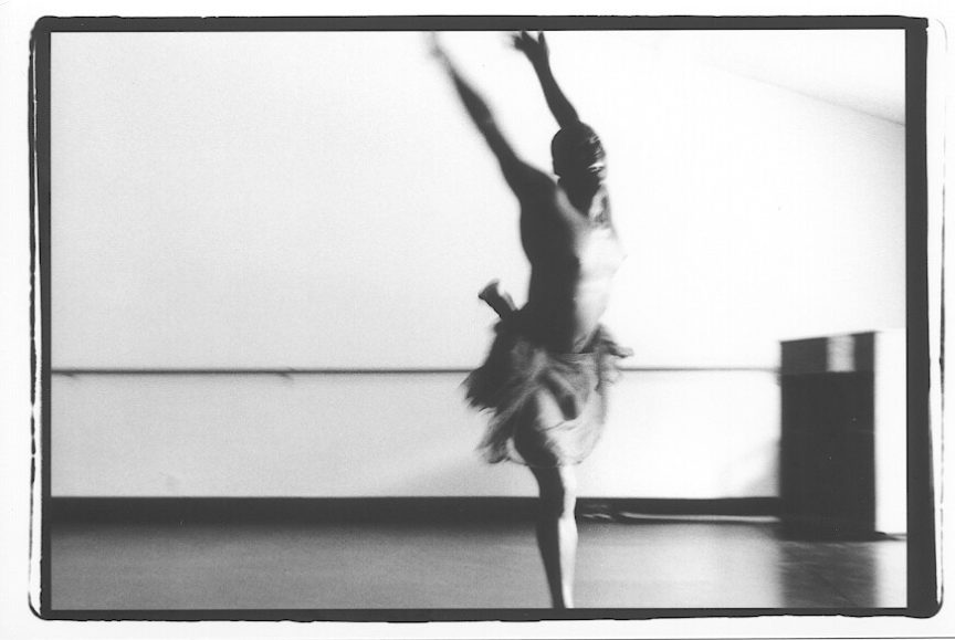 a topless ballet dance leaps in black and white
