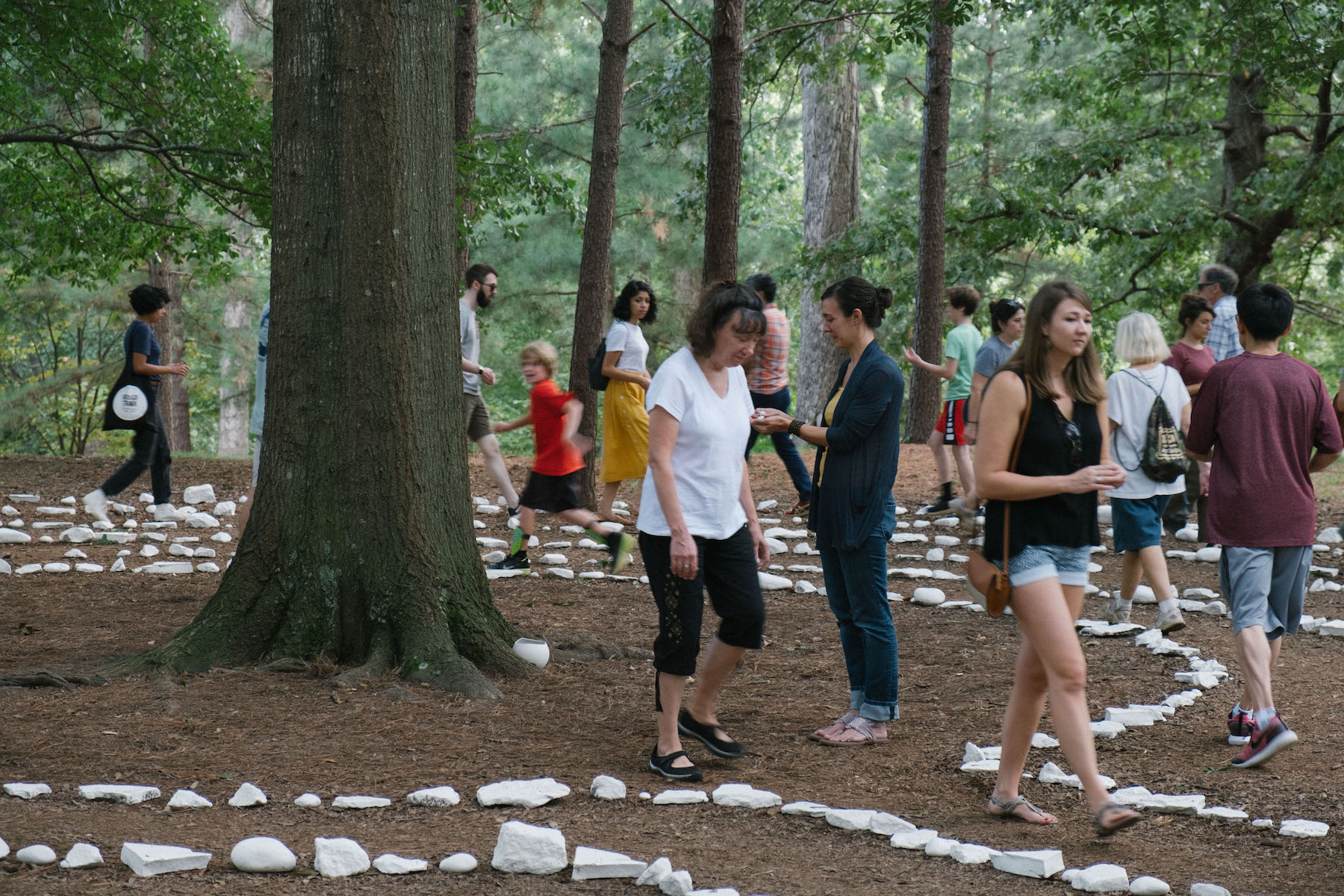a group of people of various ages stroll through the porcelain rock maze that is Passage by Rachel K. Garceau