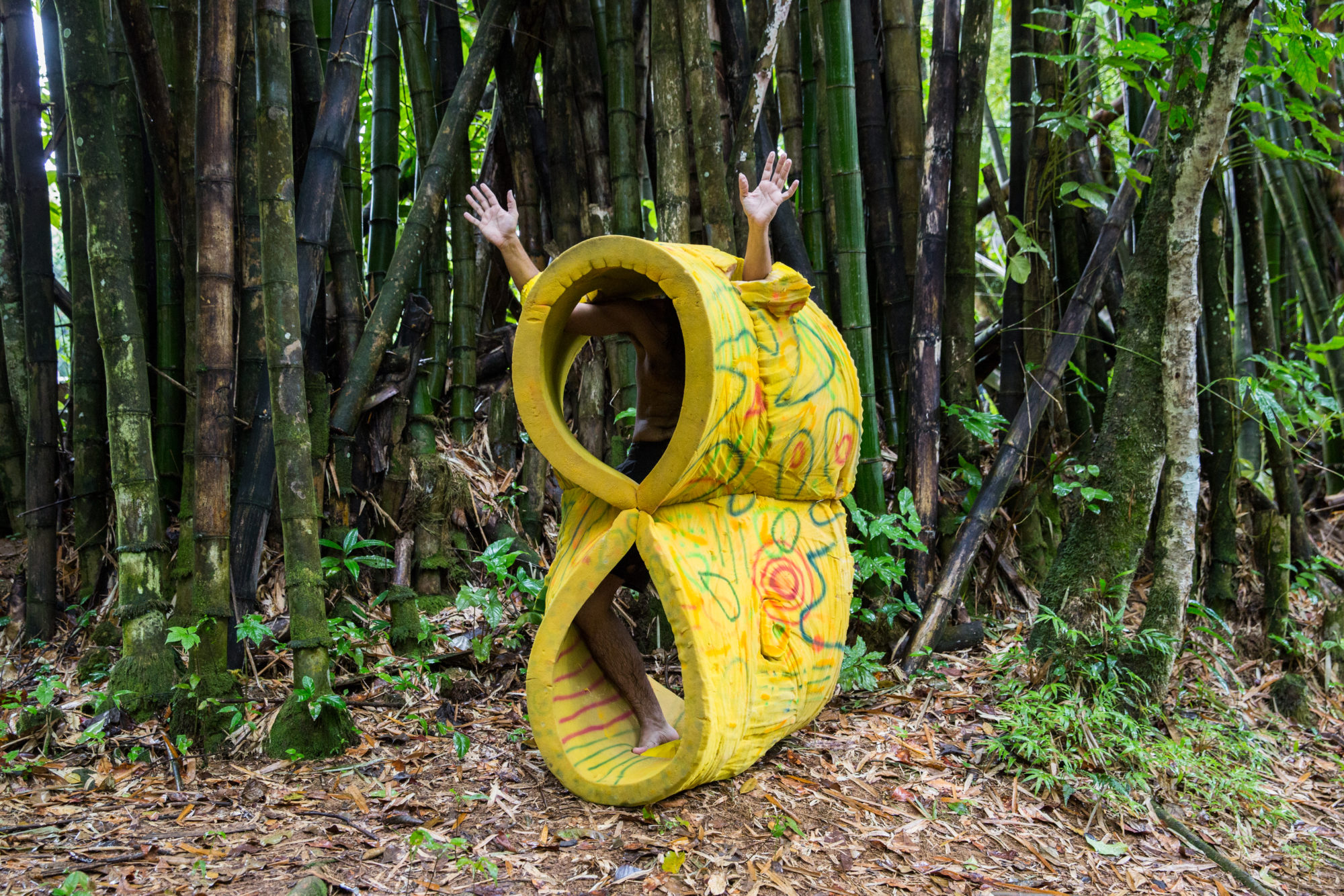 person stands in yellow foam structure among trees