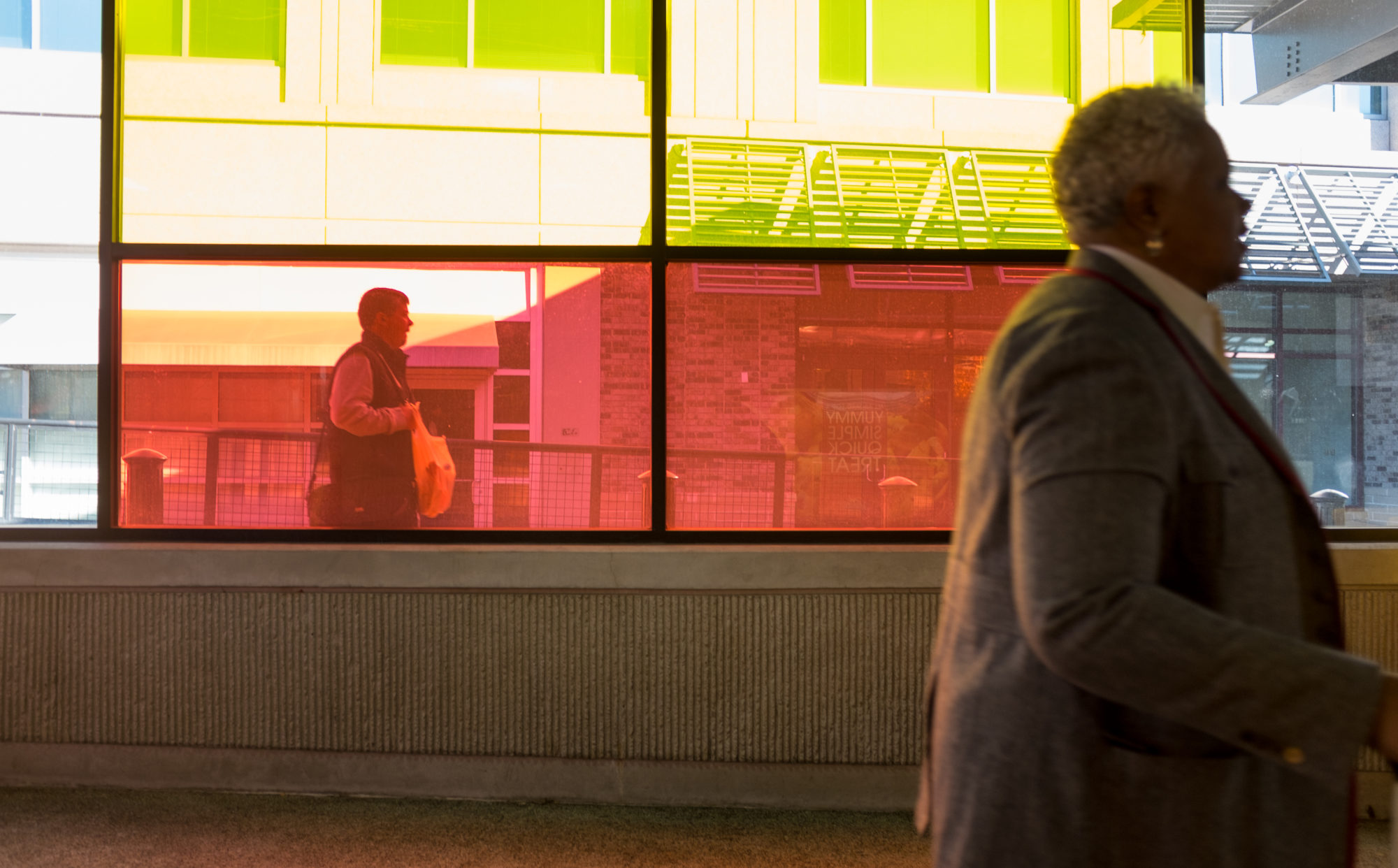 A woman walks by colorfully tinted windows