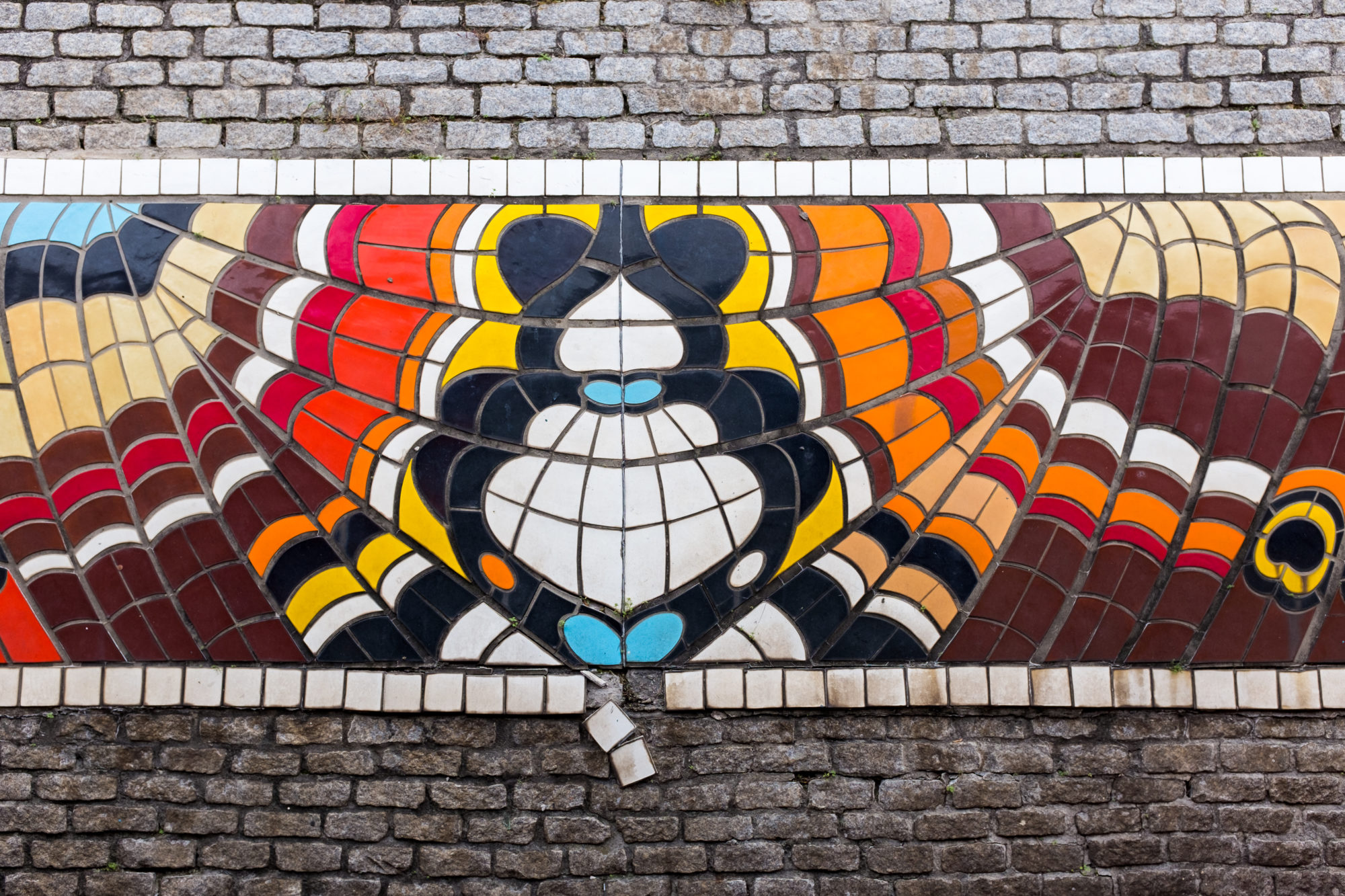 A colorful tile mural on cobblestone