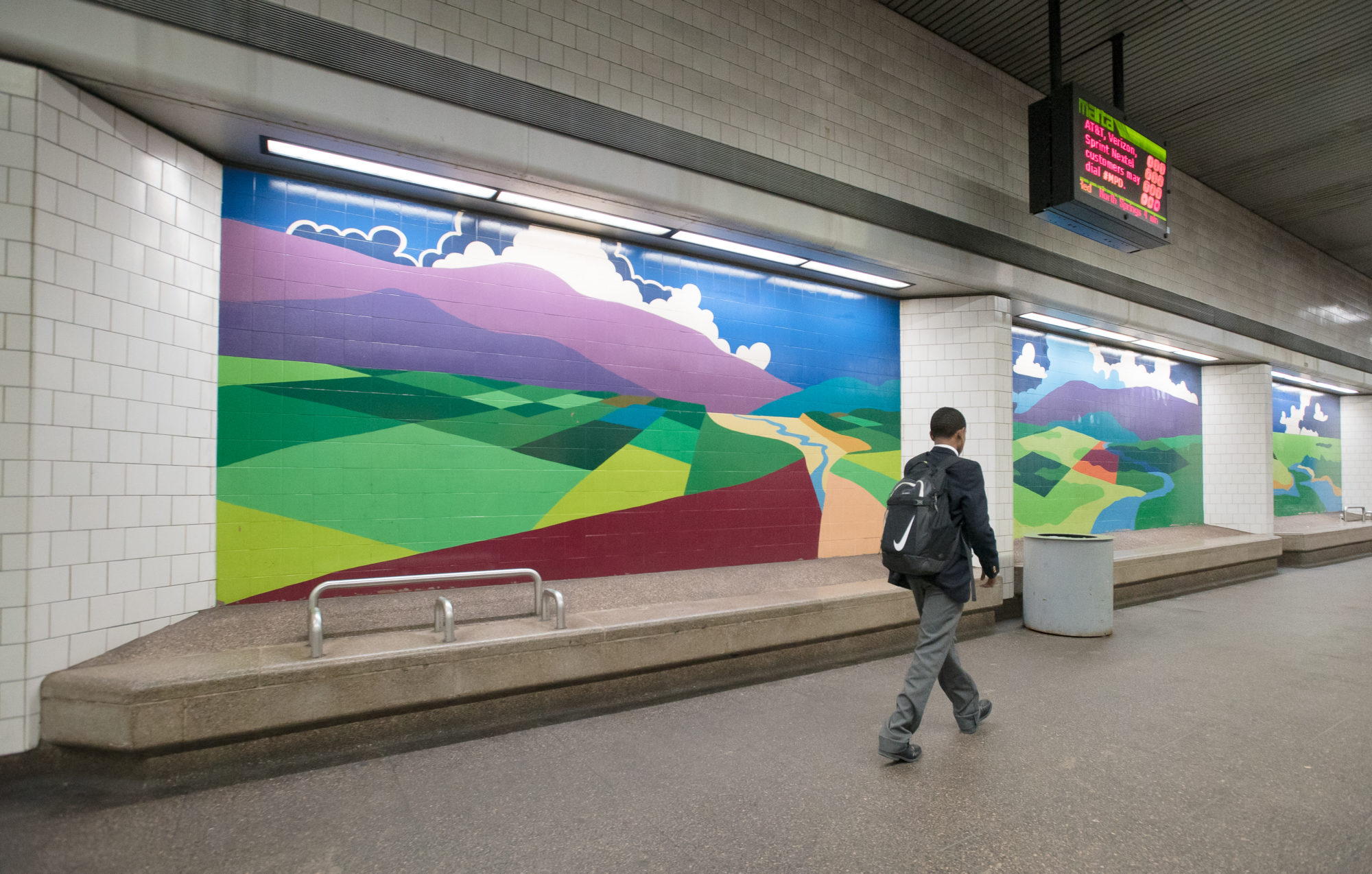 A man walks past colorfully painted murals at a train station