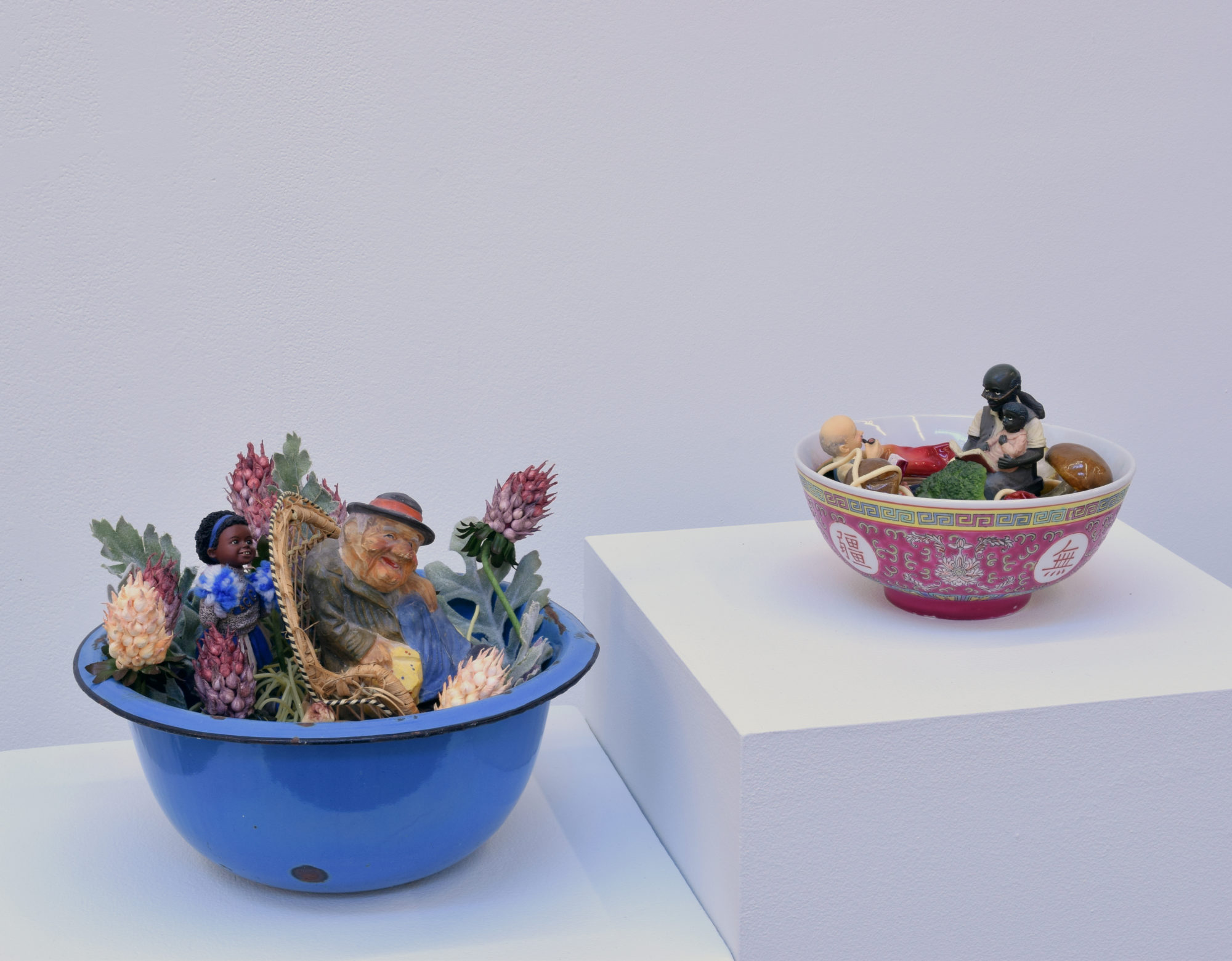 Close up of two sculptures, small dioramas in bowls, from It Can Howl