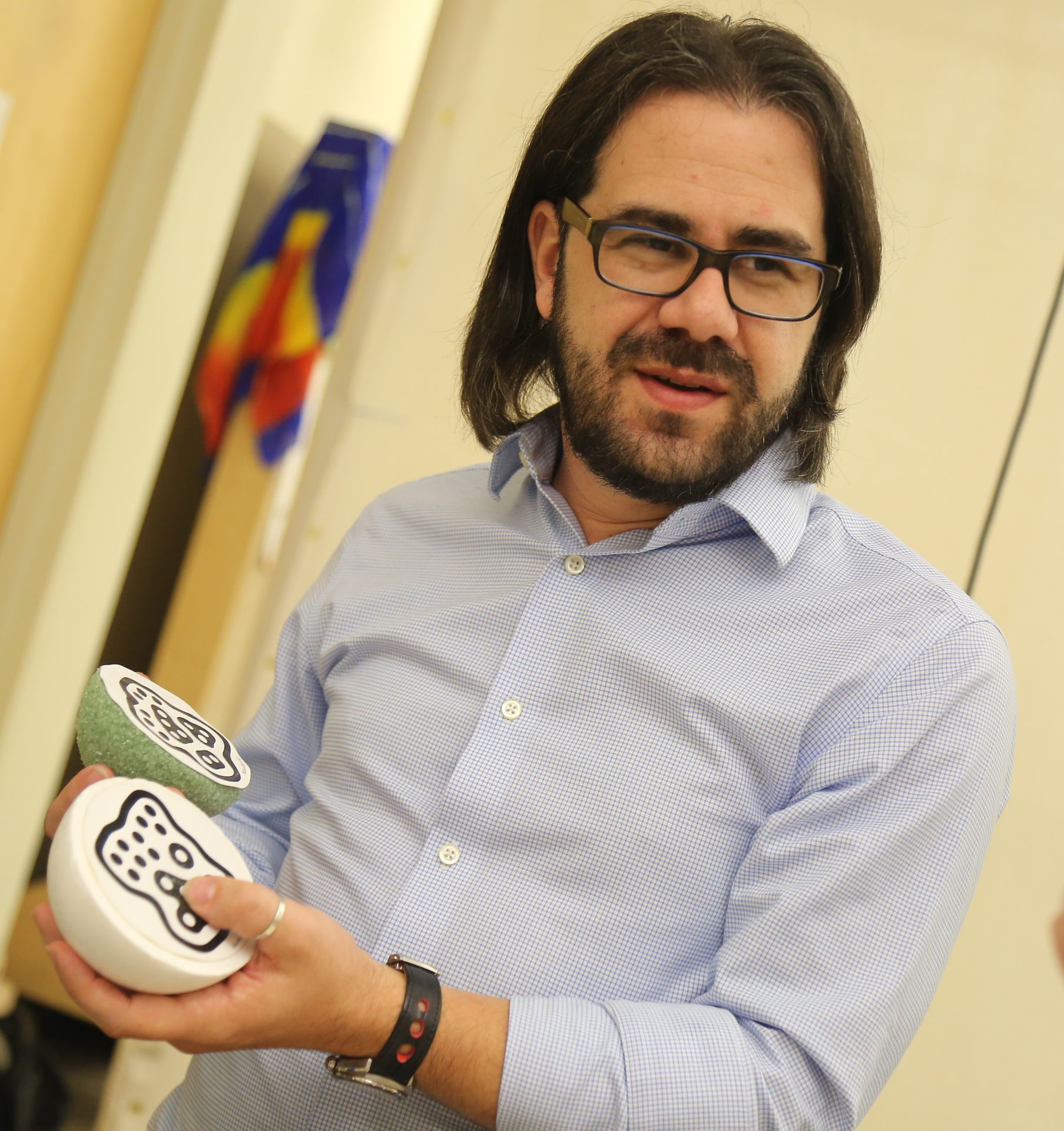 An image of Ian Bogost holding two objects, one green and one white.