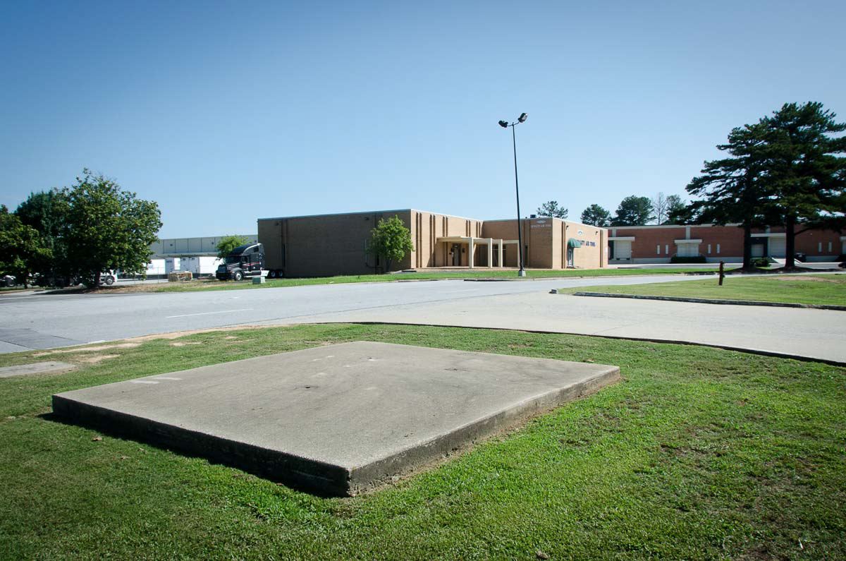 Concrete plank in the middle of grass next to a brown building