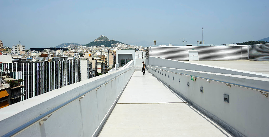 a man walking up walkway, overlooking the city and mountains
