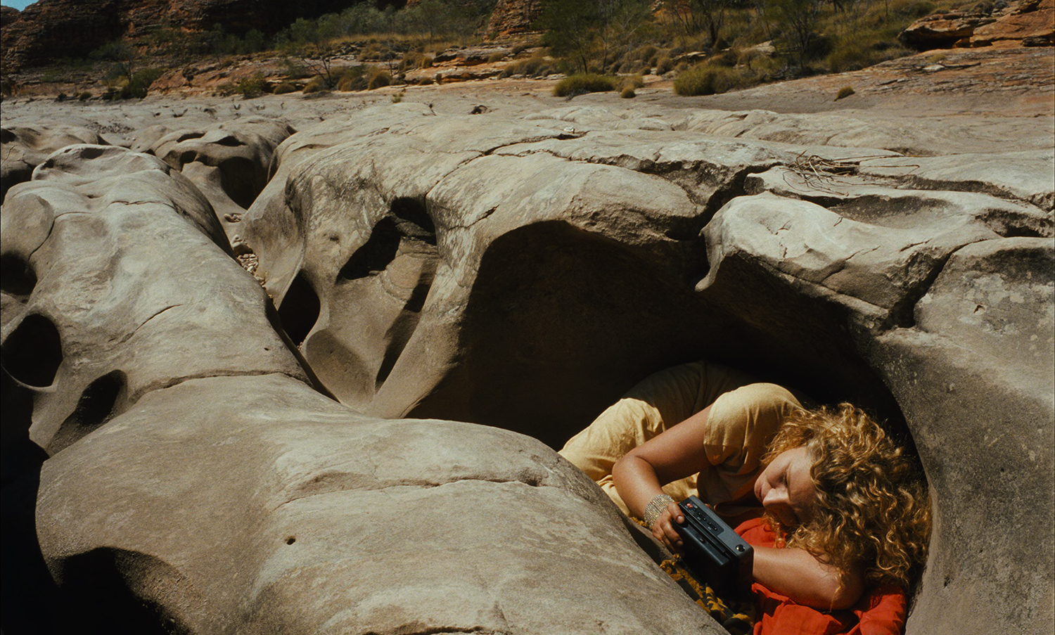 A woman laying on a rock looking at photos