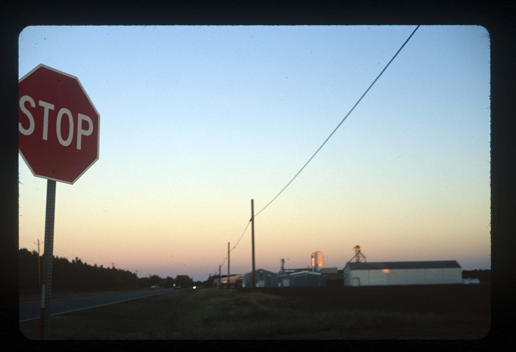 View of a stop sign, street, and buildings during a sunset