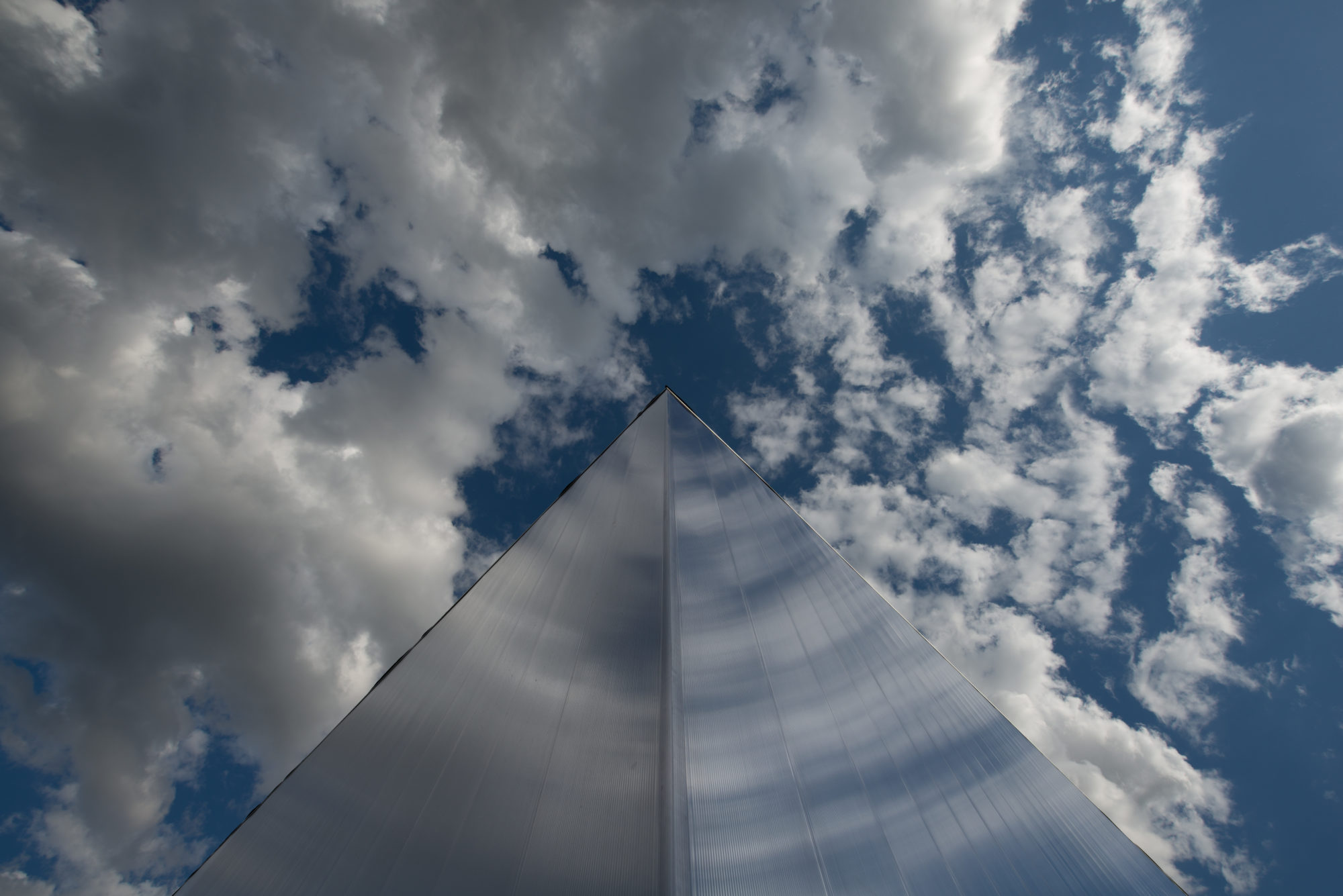 View from below of a reflective building among clouds