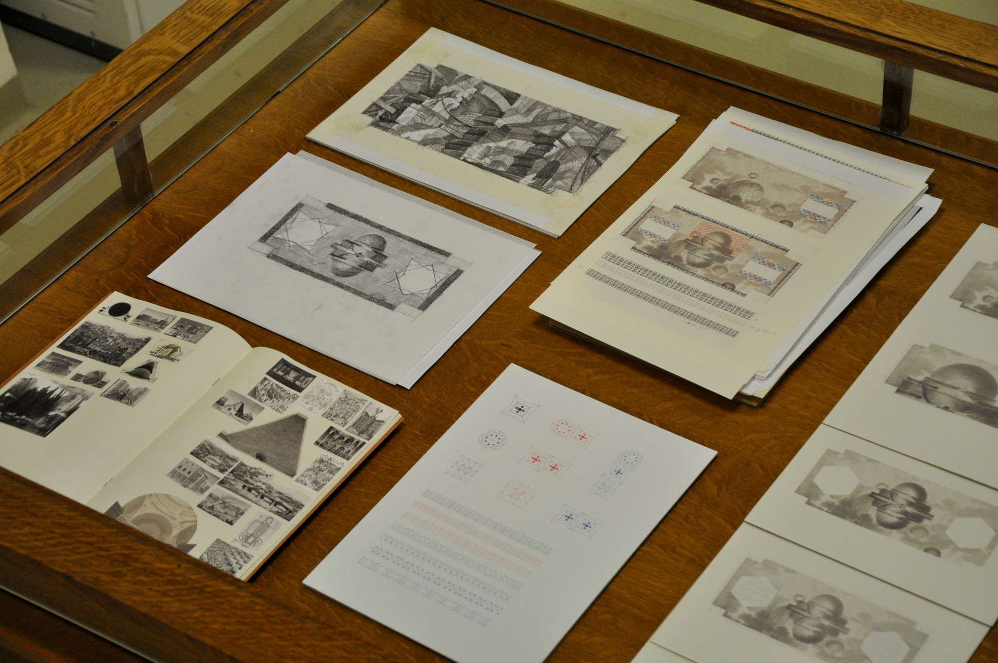 a display case contains digital prints, drawings, and collages