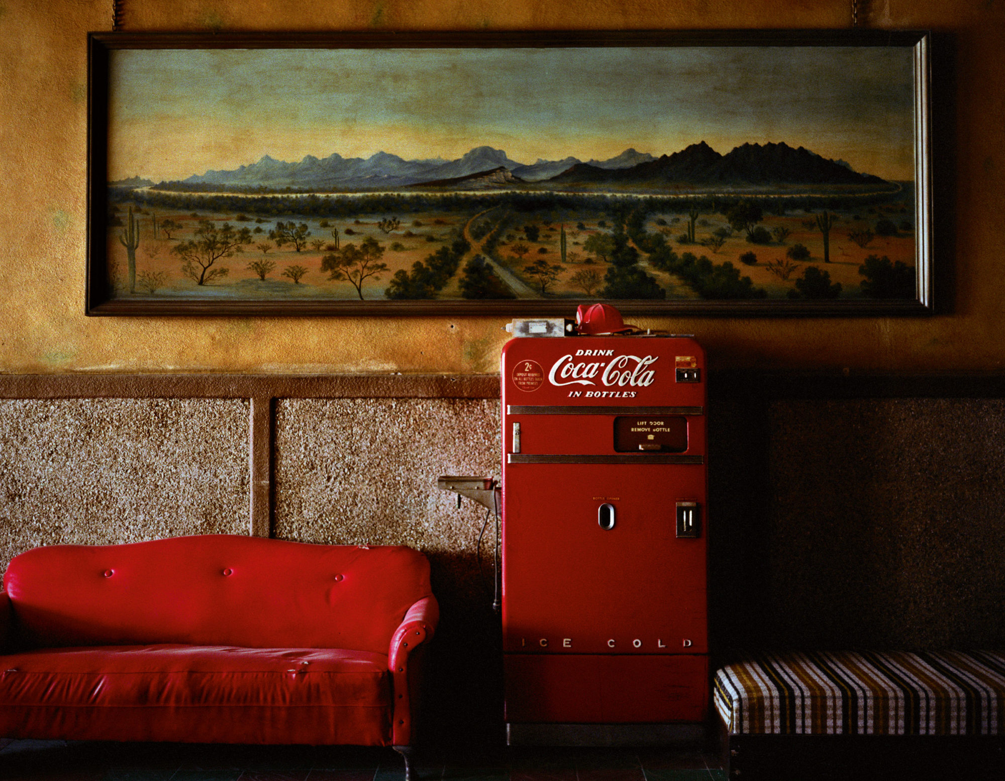 A vintage coca cola machine placed between two vintage couches