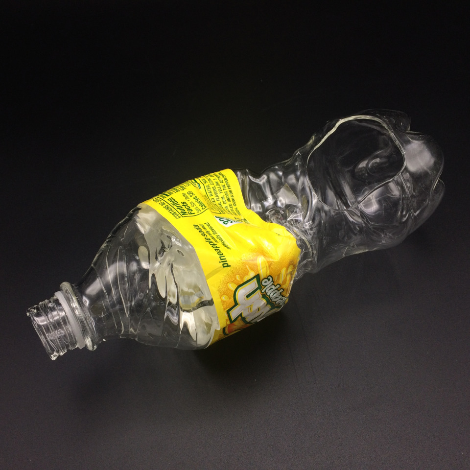 A glass urinary device shaped like a pipe with a Crush soda wrapper around it.
