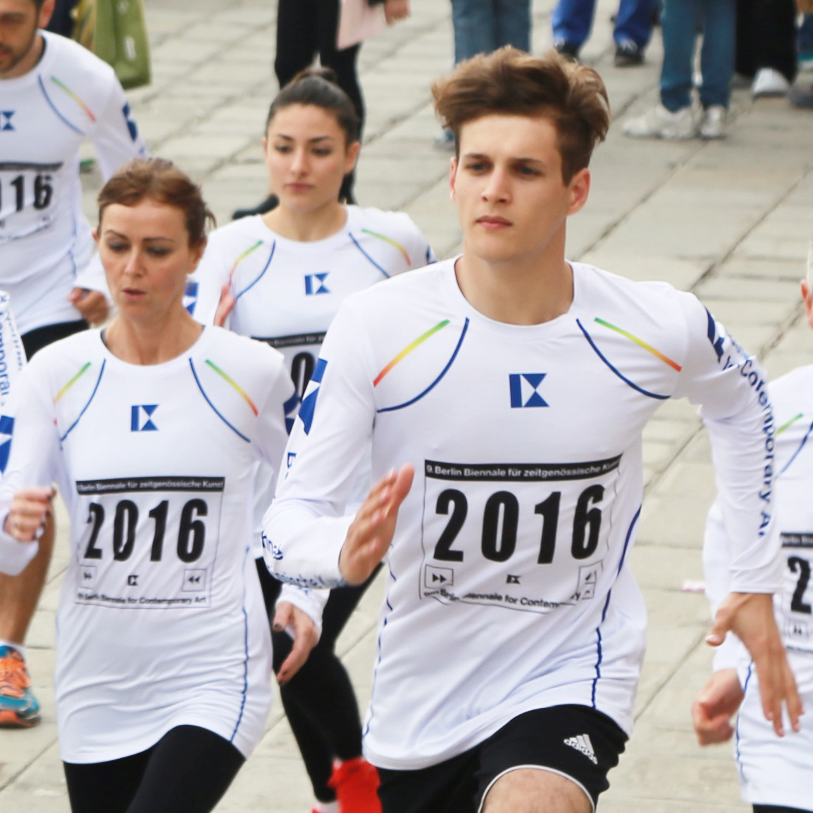 Group of men and women, wearing white long-sleeved running shirts, running