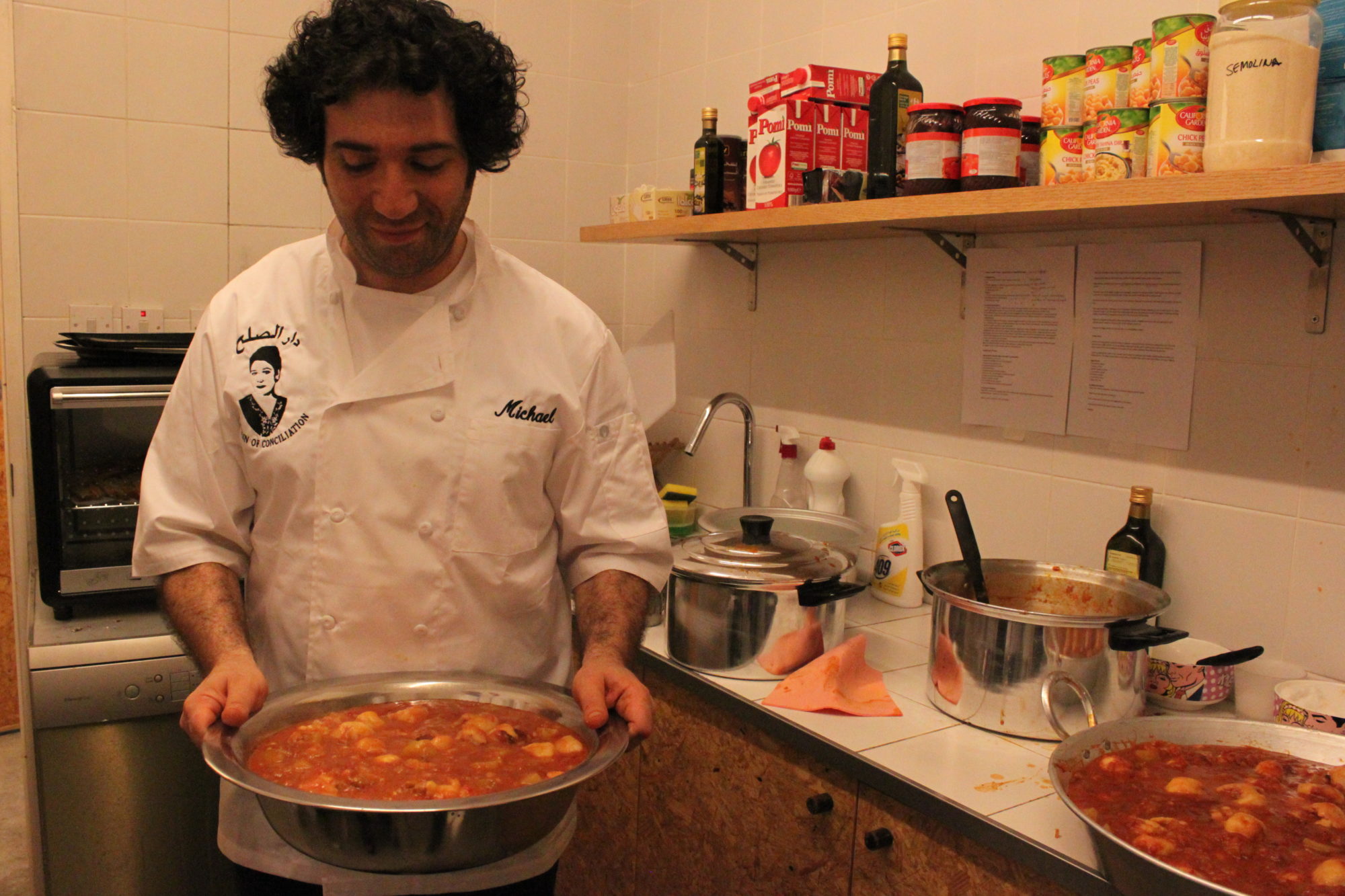 An image of a chef holding a giant silver bowl of food.